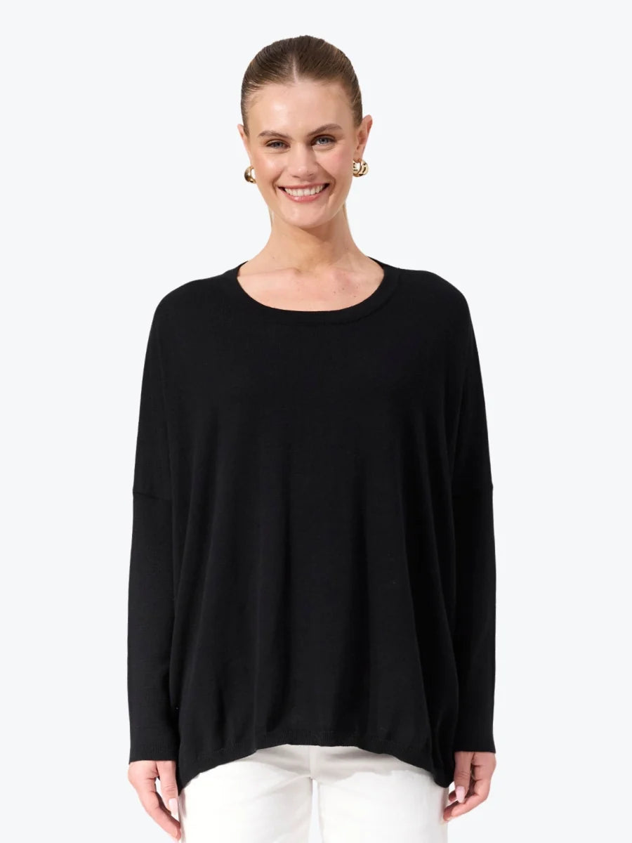 Image of Woman wearing black Haven knit paired with white jeans on a plain background 