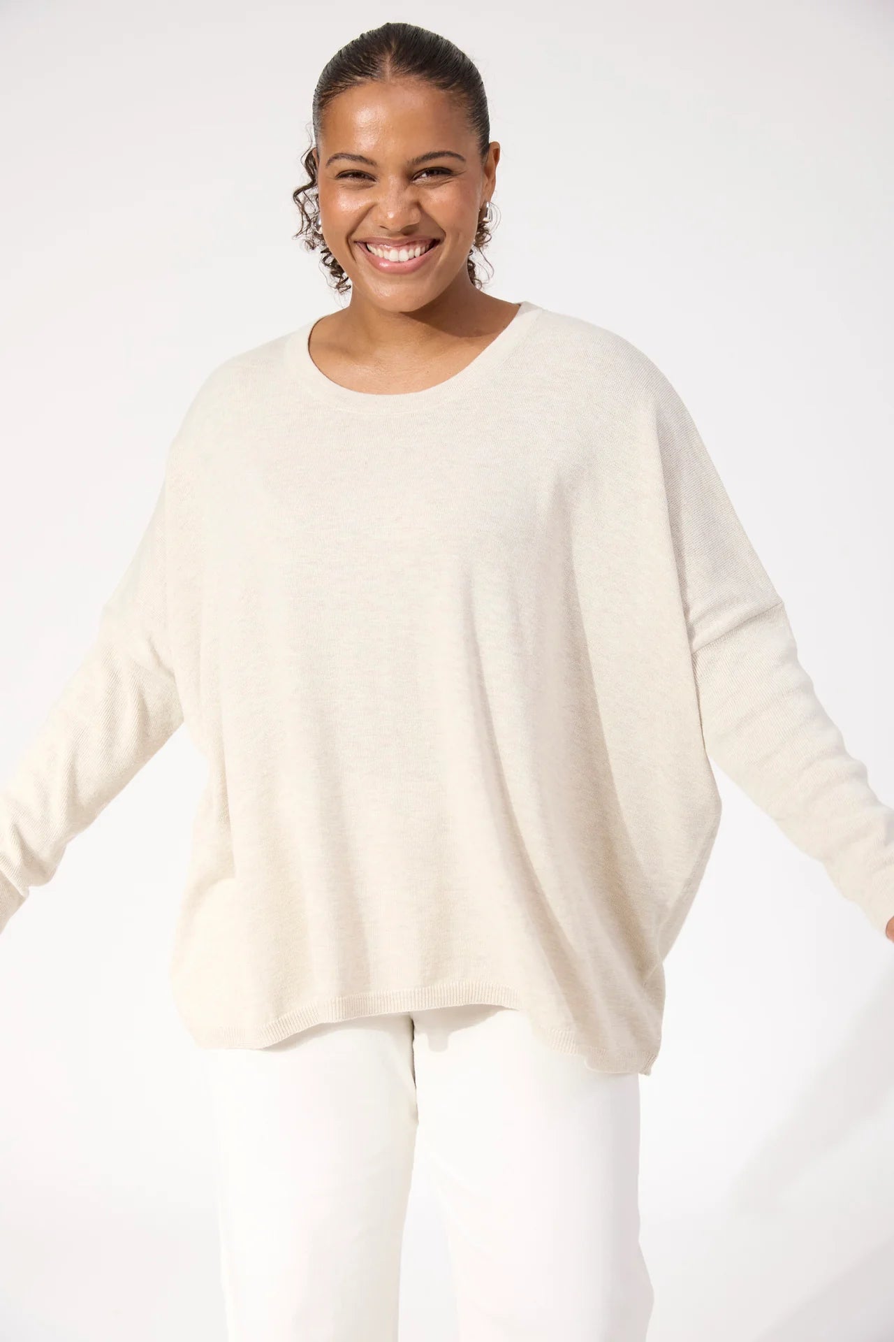 Woman wearing Haven Knit paired with white denim jeans on a plain background