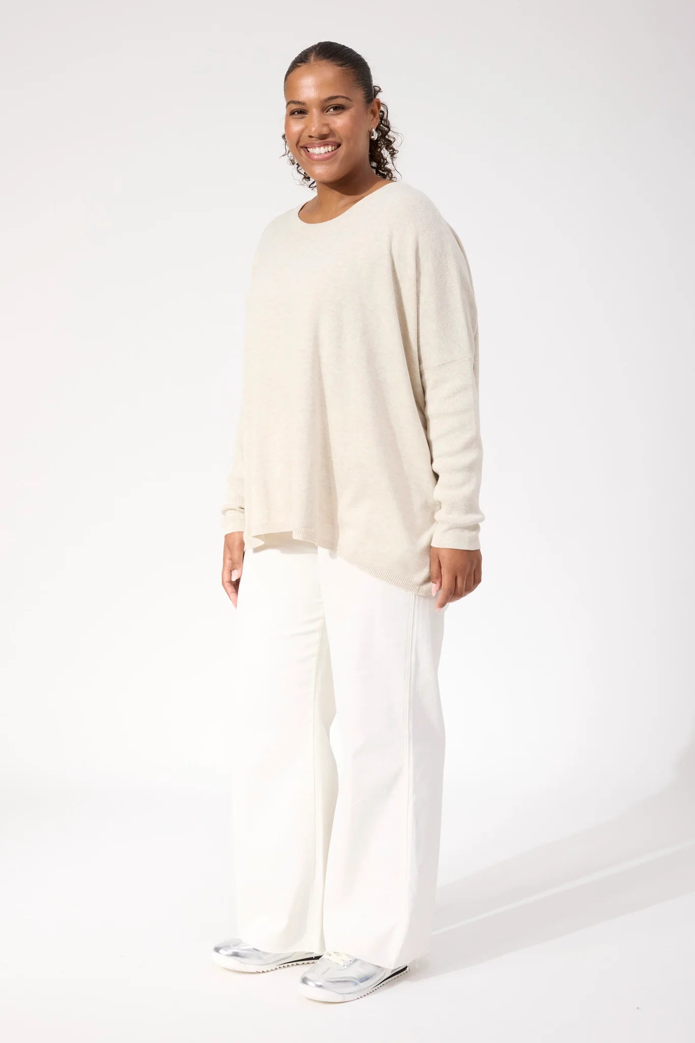 Woman wearing Haven Knit paired with white denim jeans on a plain background