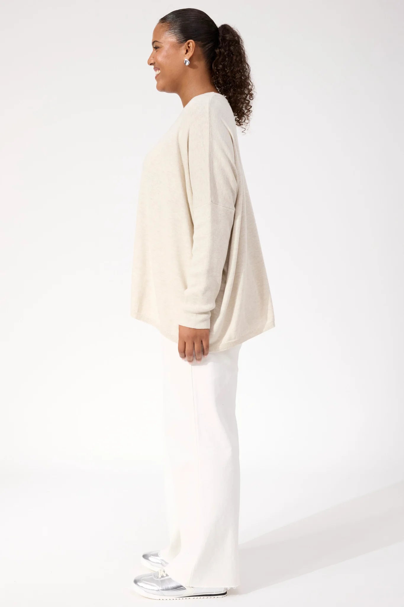 Woman wearing Haven Knit paired with white denim jeans on a plain background