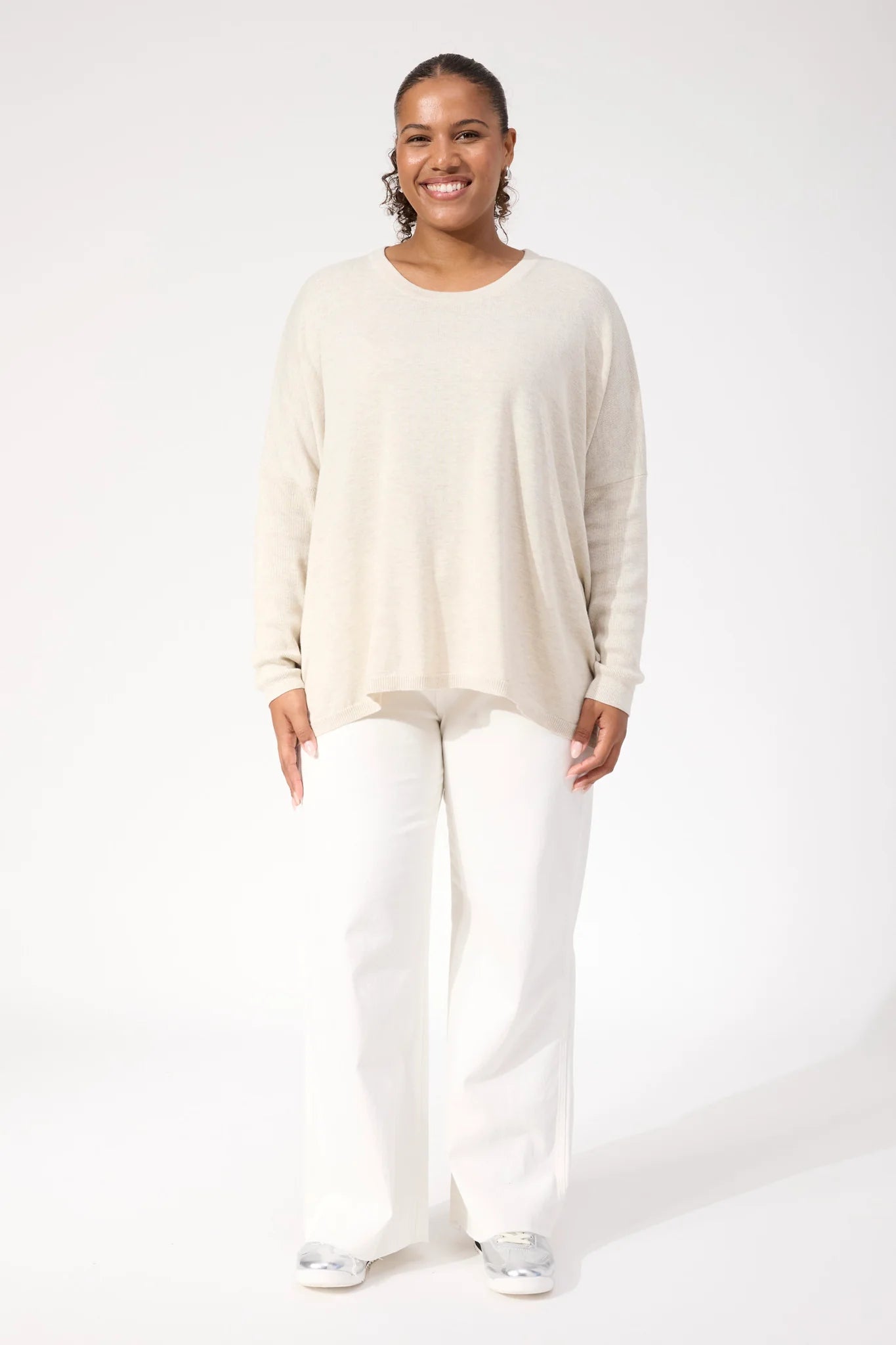 Woman wearing Haven Knit paired with white denim jeans on a plain background