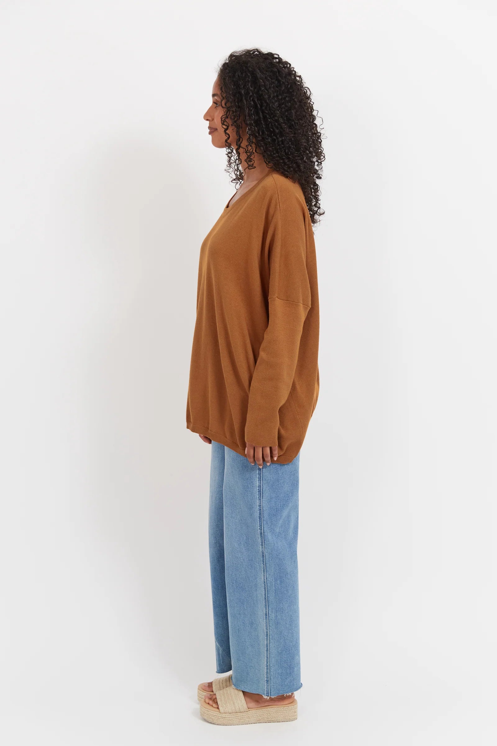 Woman wearing tan Haven knit paired with denim jeans on a plain background