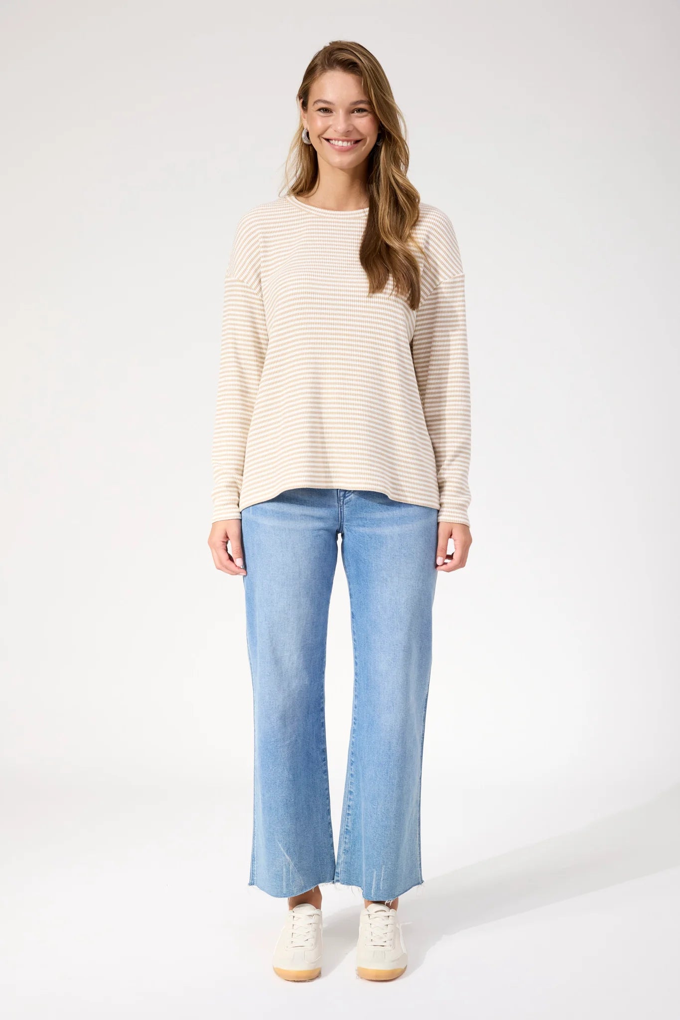 Image of Woman wearing Haven stripe long sleeve top paired with denim jeans on a plain background 