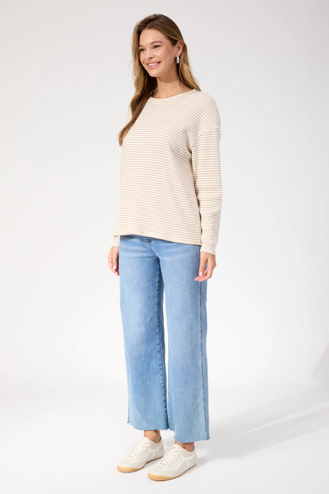 Image of Woman wearing Haven stripe long sleeve top paired with denim jeans on a plain background 