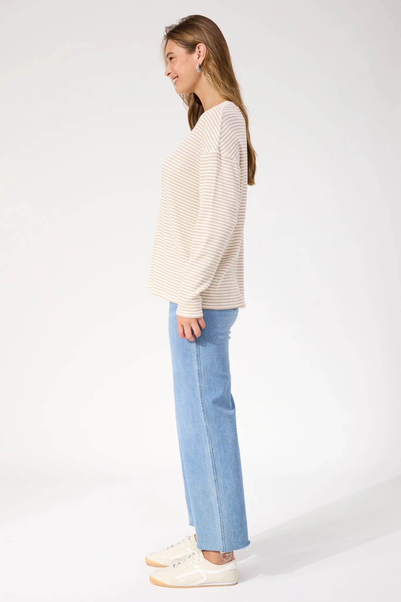Image of Woman wearing Haven stripe long sleeve top paired with denim jeans on a plain background 