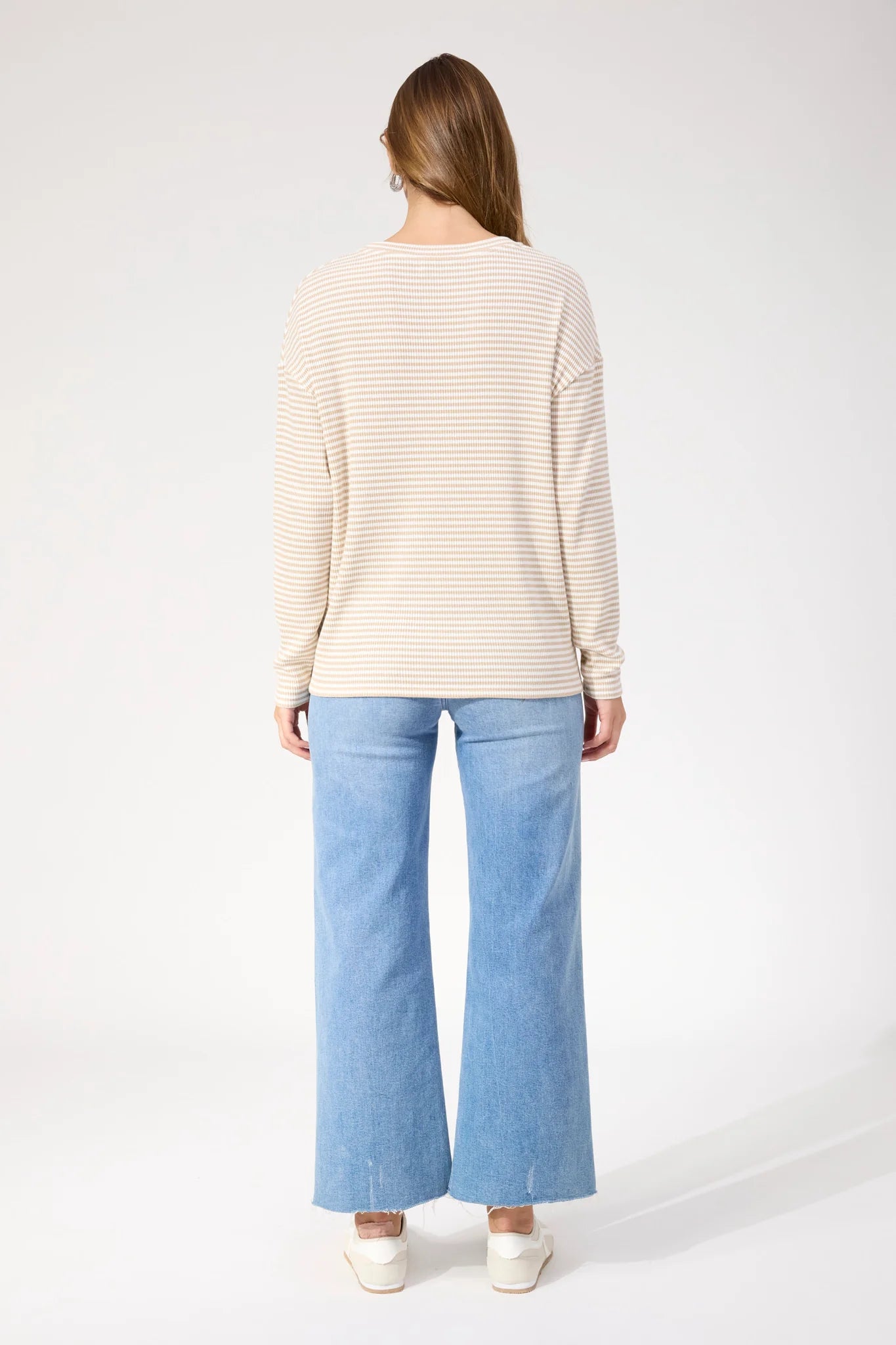 Image of Woman wearing Haven stripe long sleeve top paired with denim jeans on a plain background 