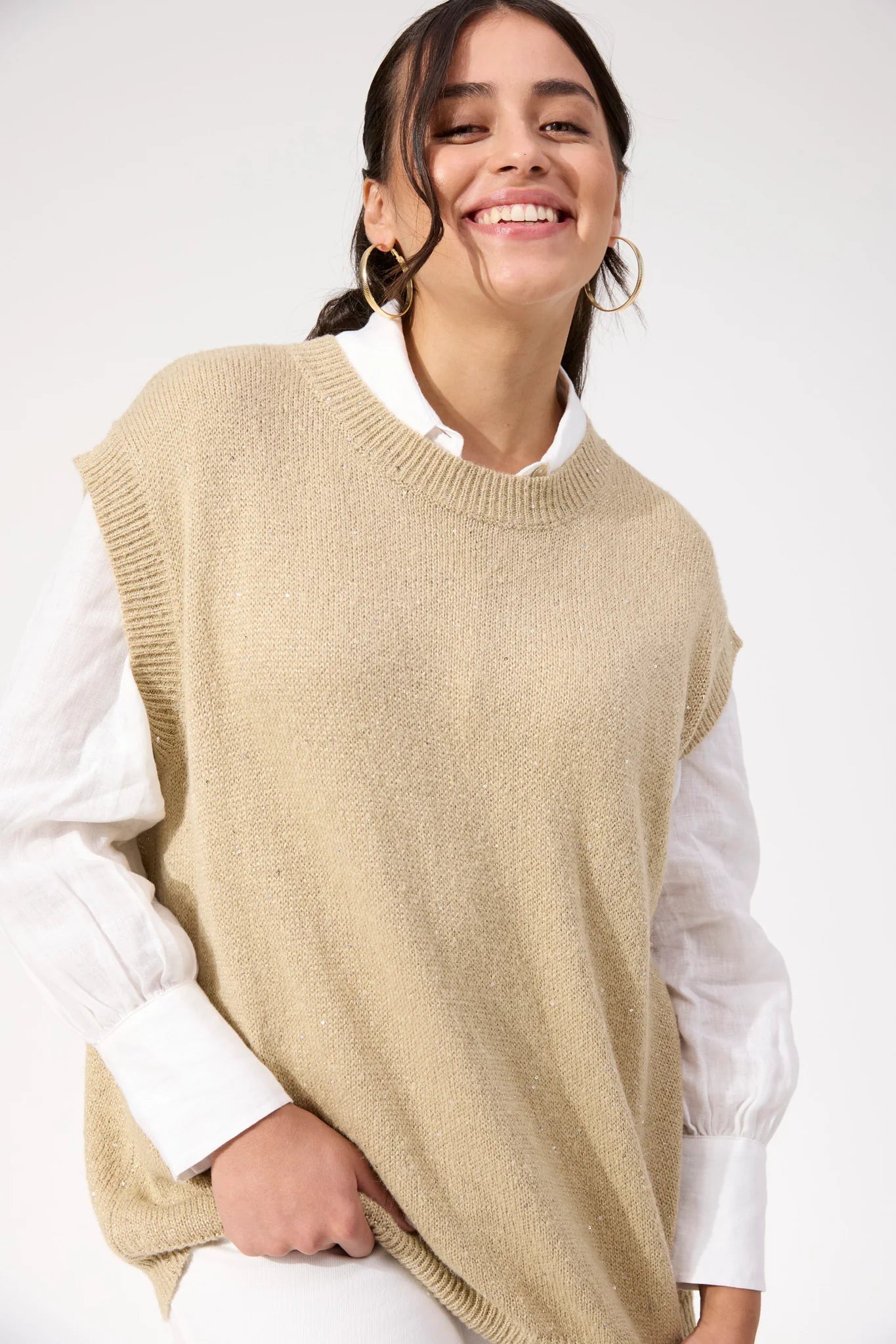 Woman wearing Haven sparkle vest paired with white jeans on a plain background