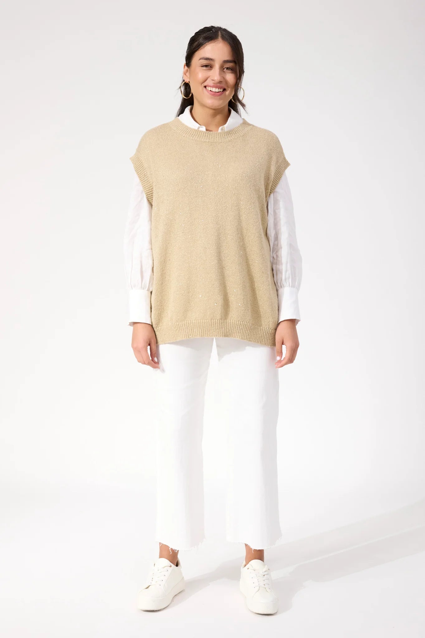 Woman wearing Haven sparkle vest paired with white jeans on a plain background