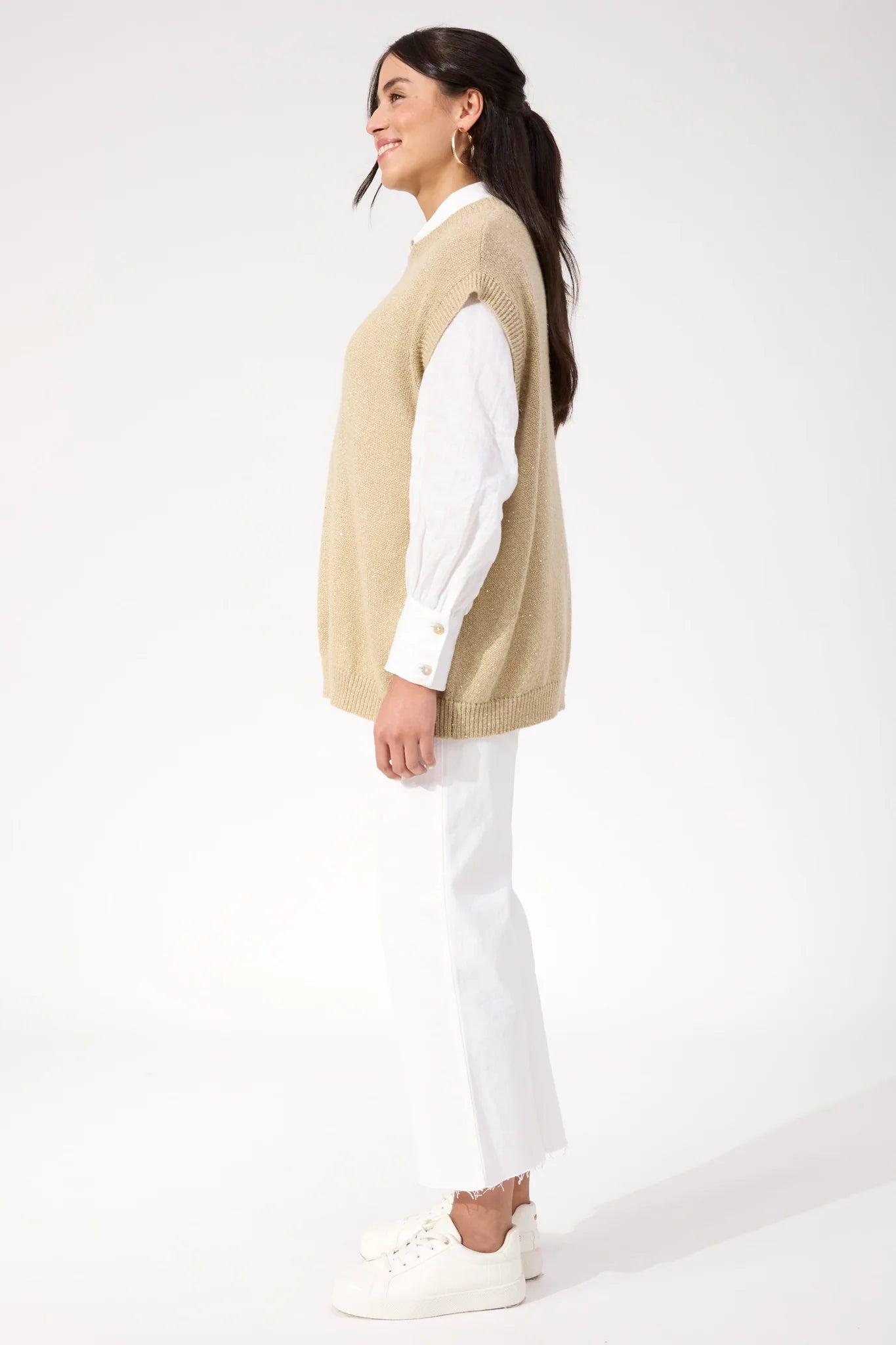 Image of Woman wearing Haven sparkle vest paired with white jeans on a plain background