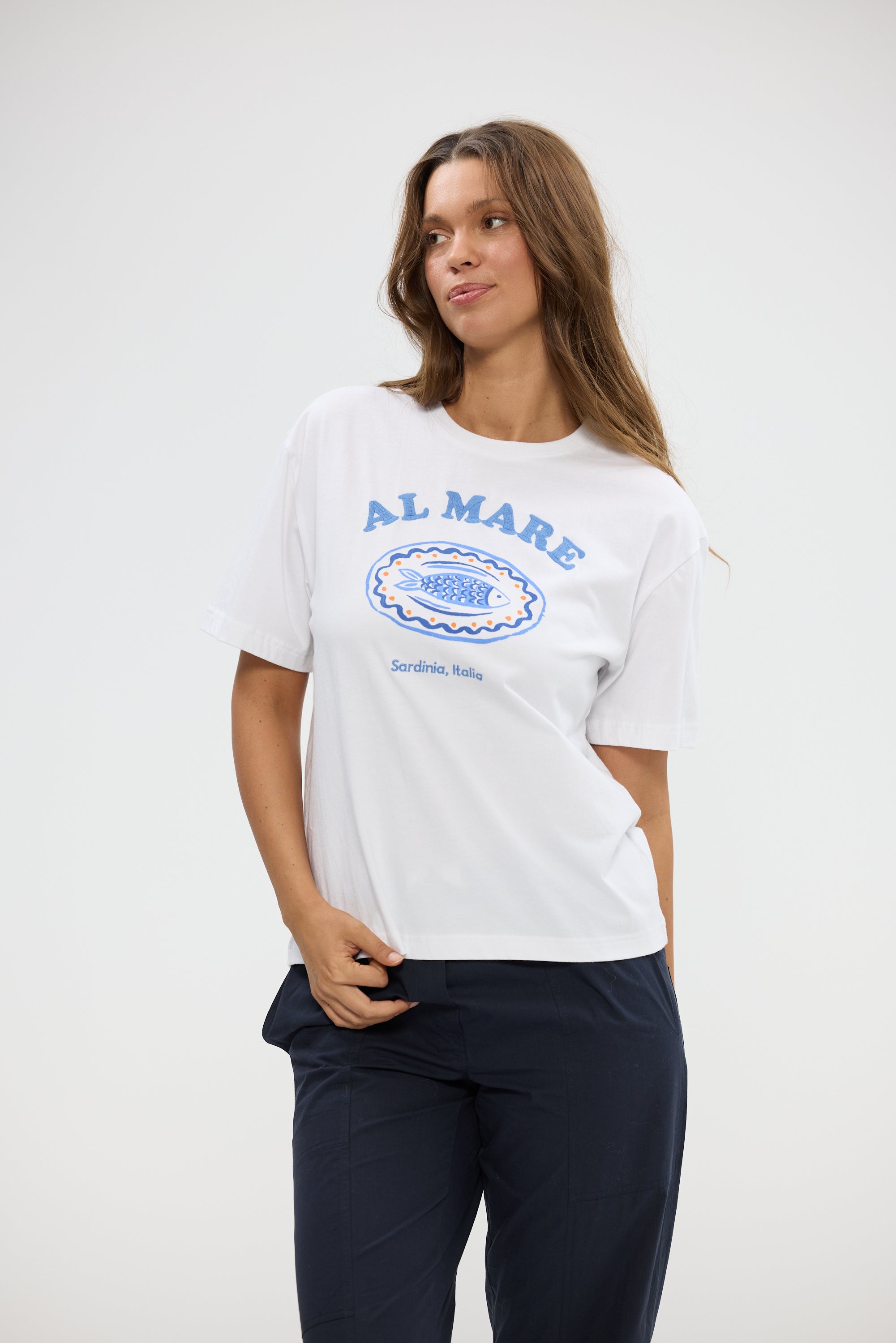 Image of Woman wearing a Holiday white t-shirt with blue text and graphics on a plain background