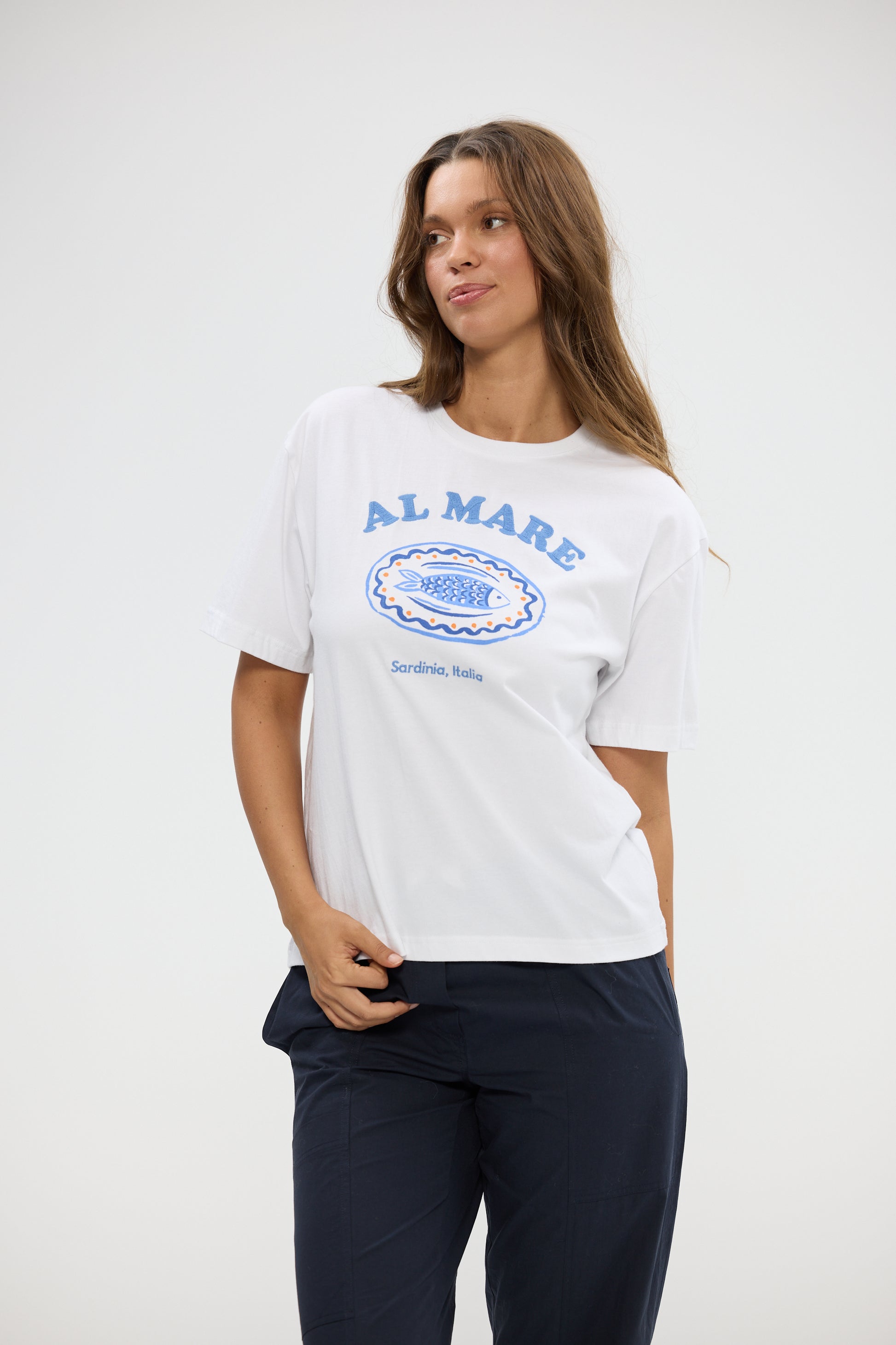 Woman wearing a Holiday white t-shirt with blue text and graphics on a plain background