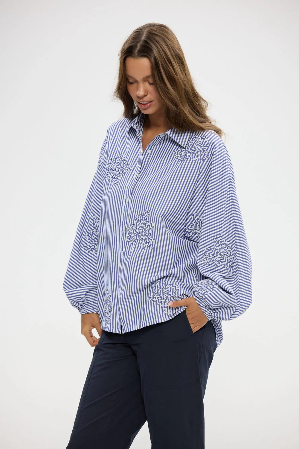 Image of Woman wearing a Holiday blue and white striped shirt with embroidery on a white background