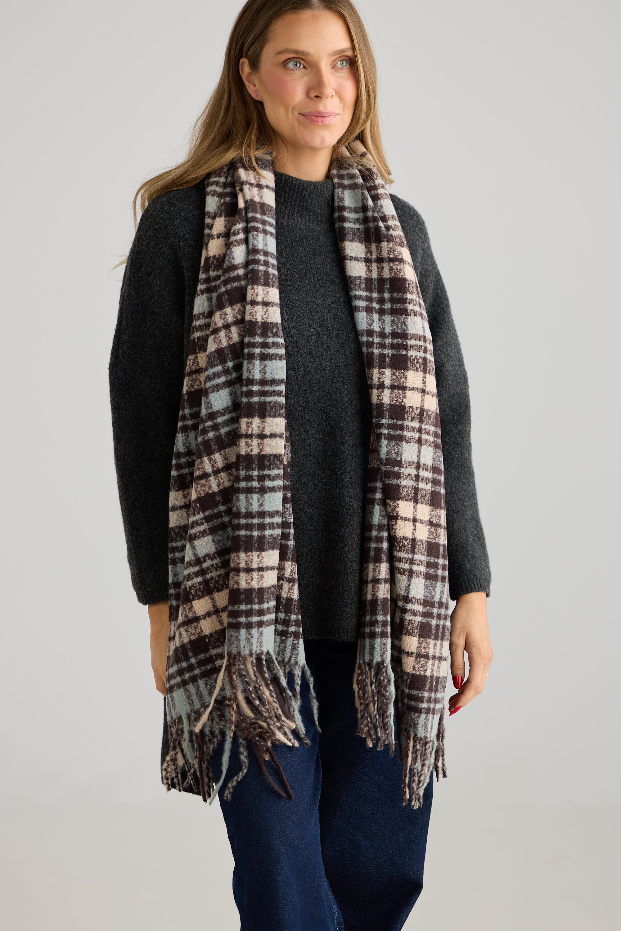 Image of Woman wearing a Holiday Life plaid scarf on a plain background