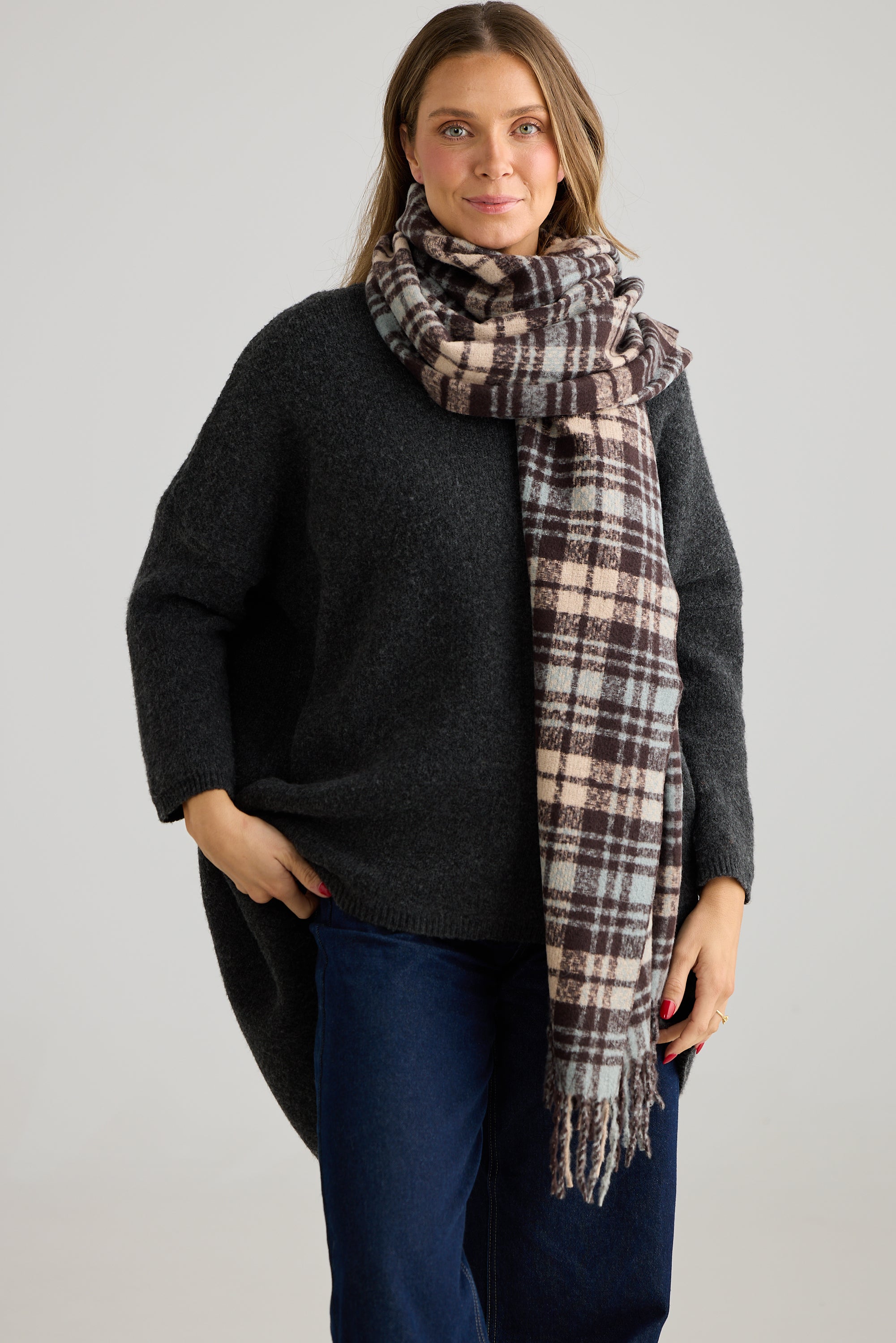 Image of Woman wearing a black sweater and Humidity plaid scarf on a gray background