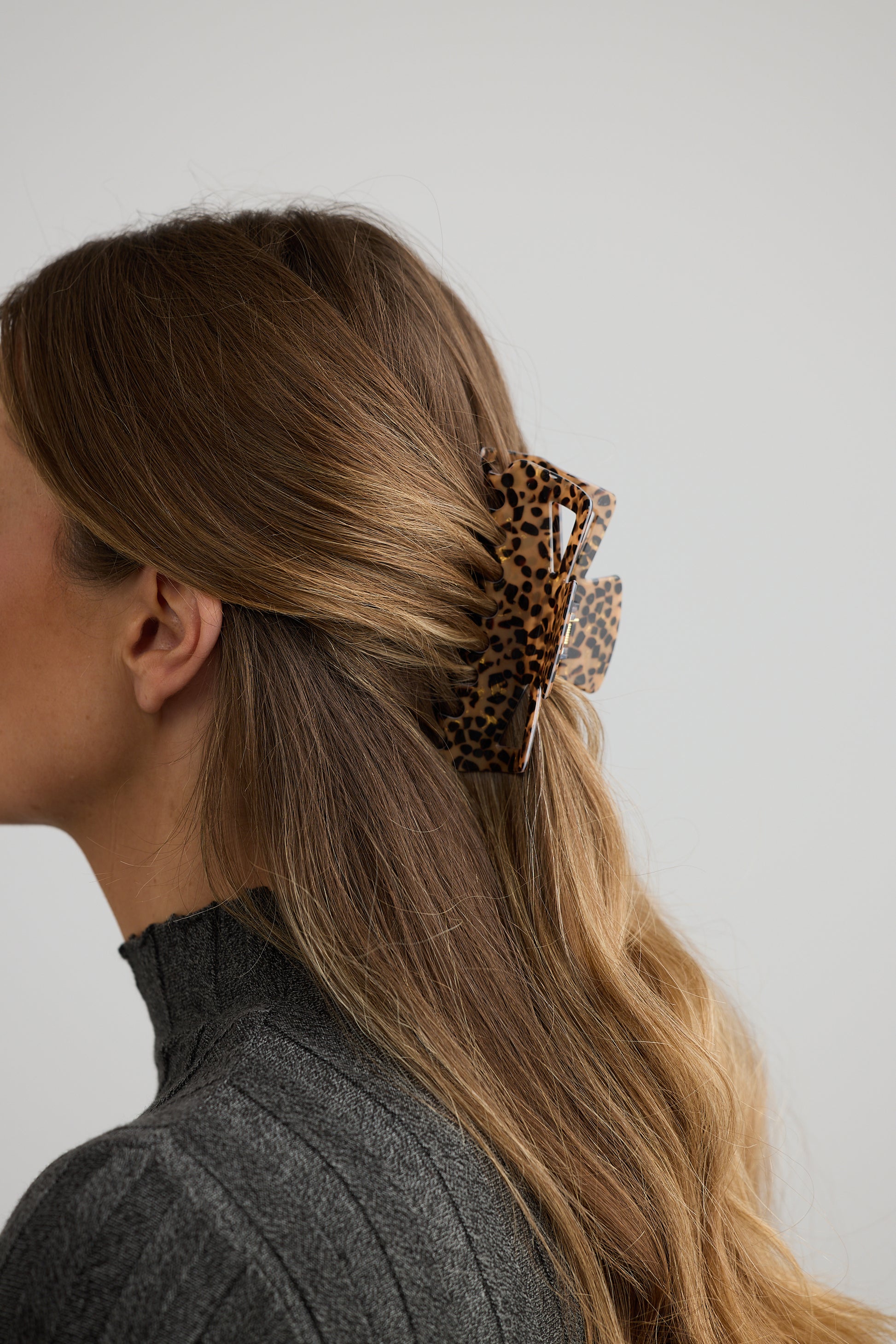 Woman with a Holiday Life leopard print hair clip in her ponytail against a plain background