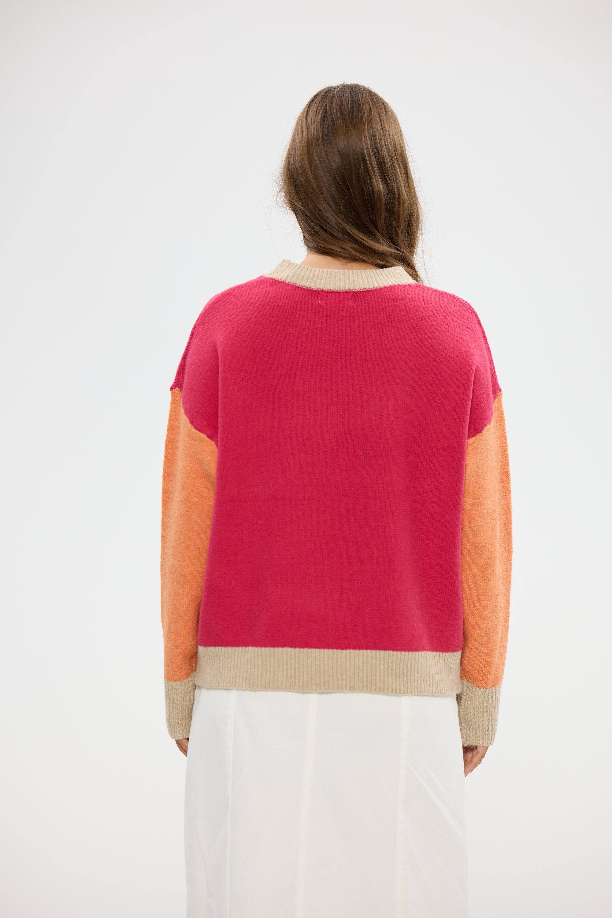 Image of Woman wearing a Holiday color-blocked sweater with pink, orange, and beige sections on a white background