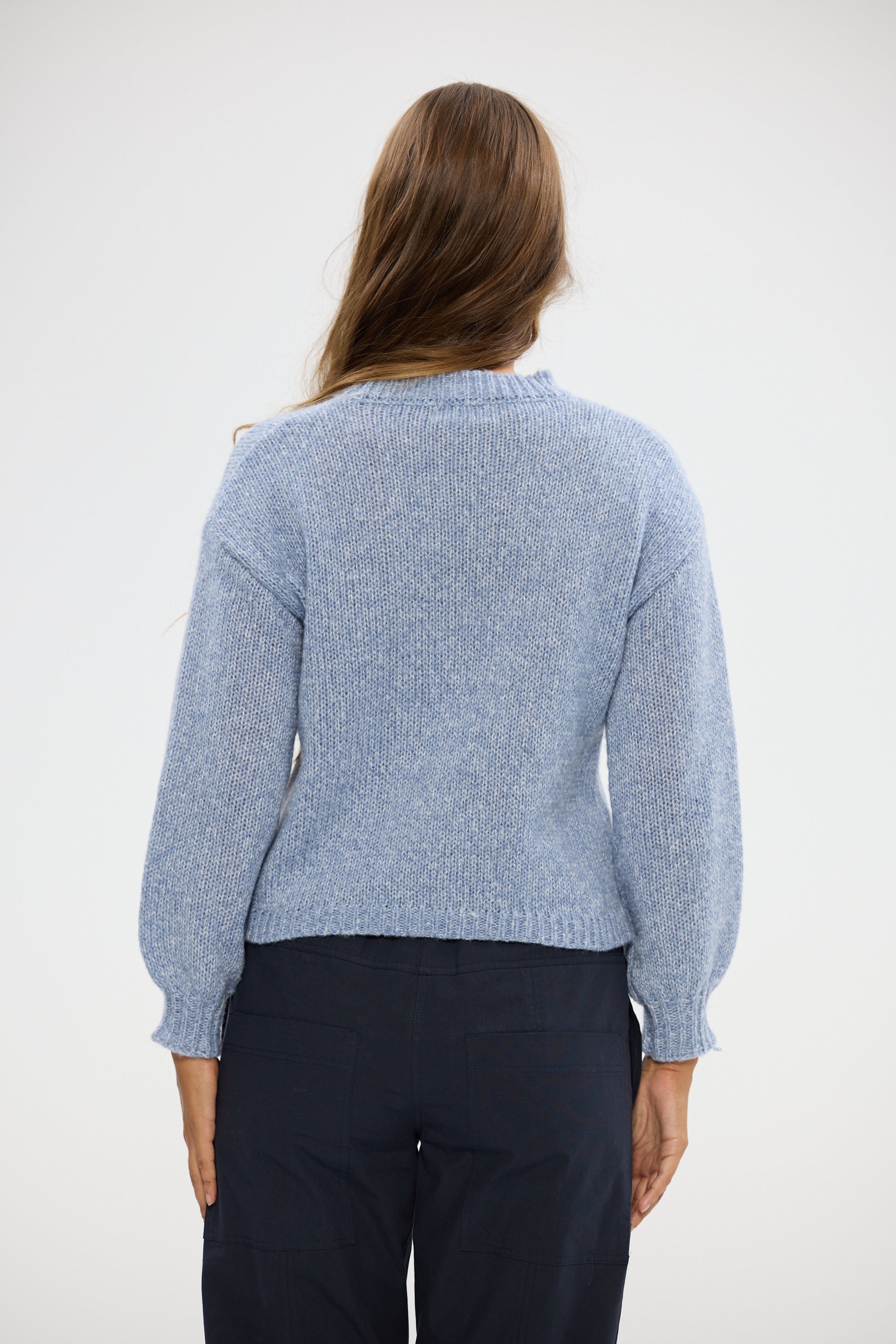 Woman wearing a Holiday light blue sweater against a white background