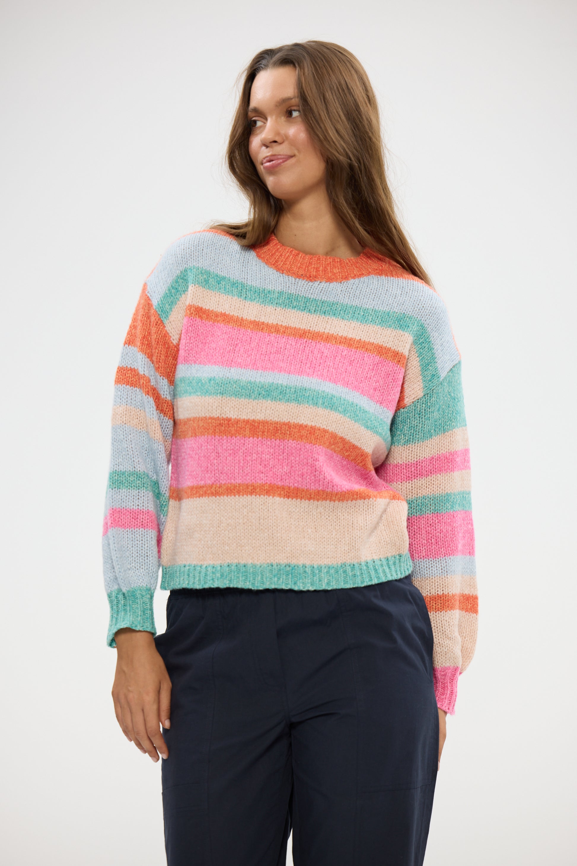Woman wearing a Holiday colorful striped sweater against a white background