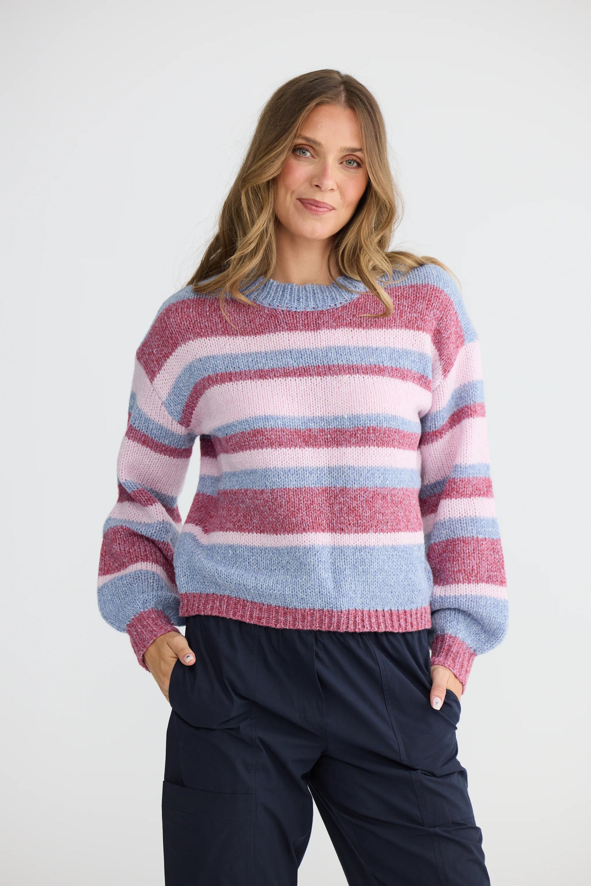 Woman wearing a Holiday multicolored striped sweater against a white background