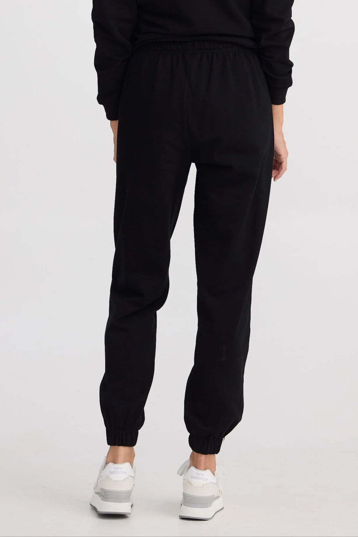 Person wearing black jogger pants on a white background