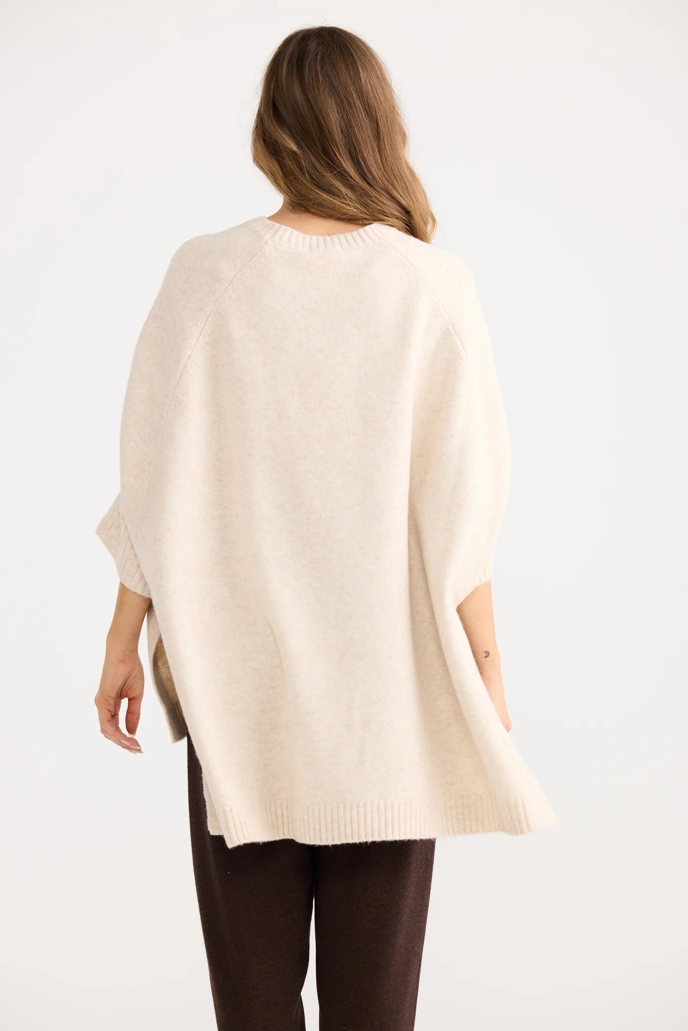 Woman wearing a Home Love beige poncho over a white background