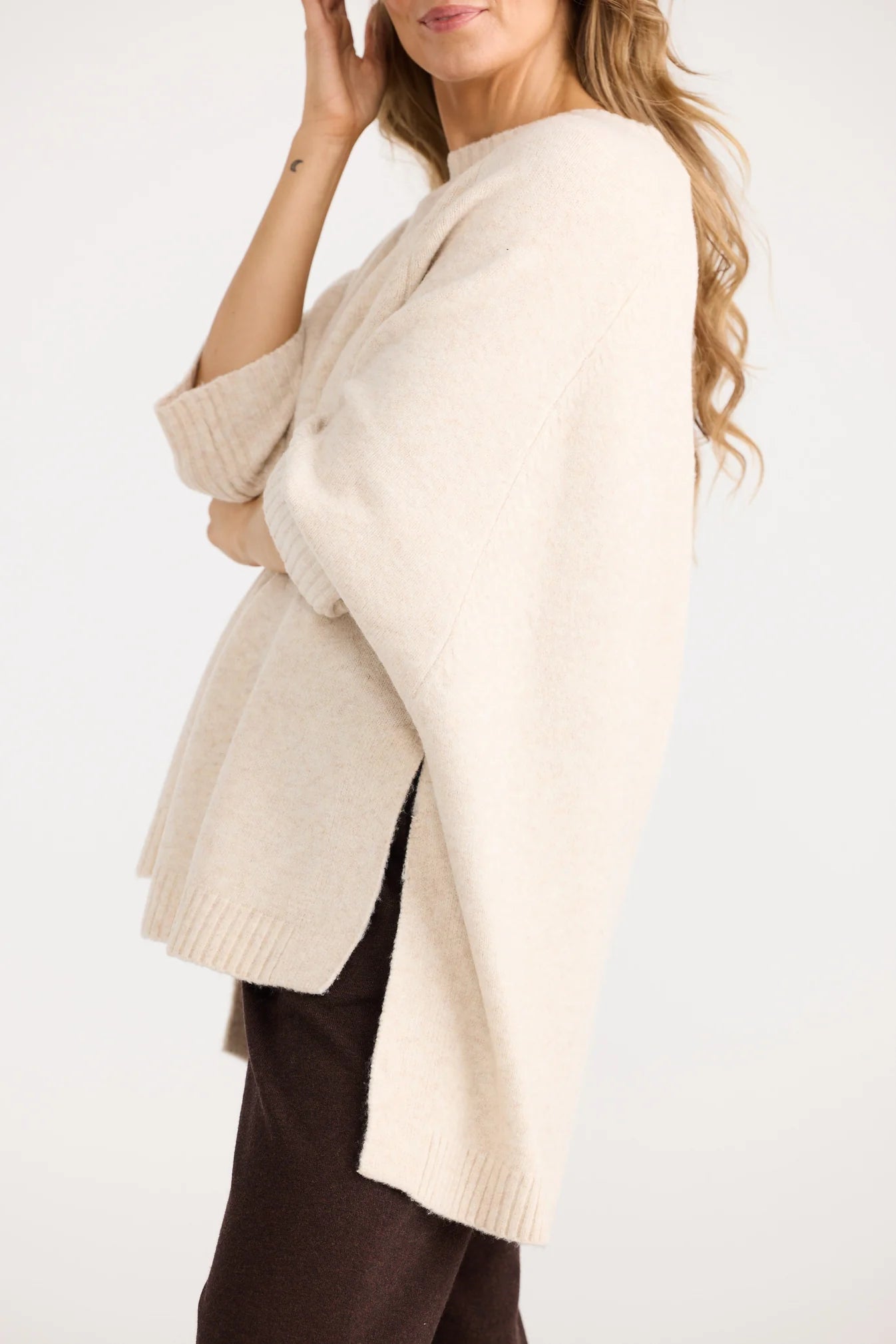 Woman wearing a Home Love beige sweater against a white background