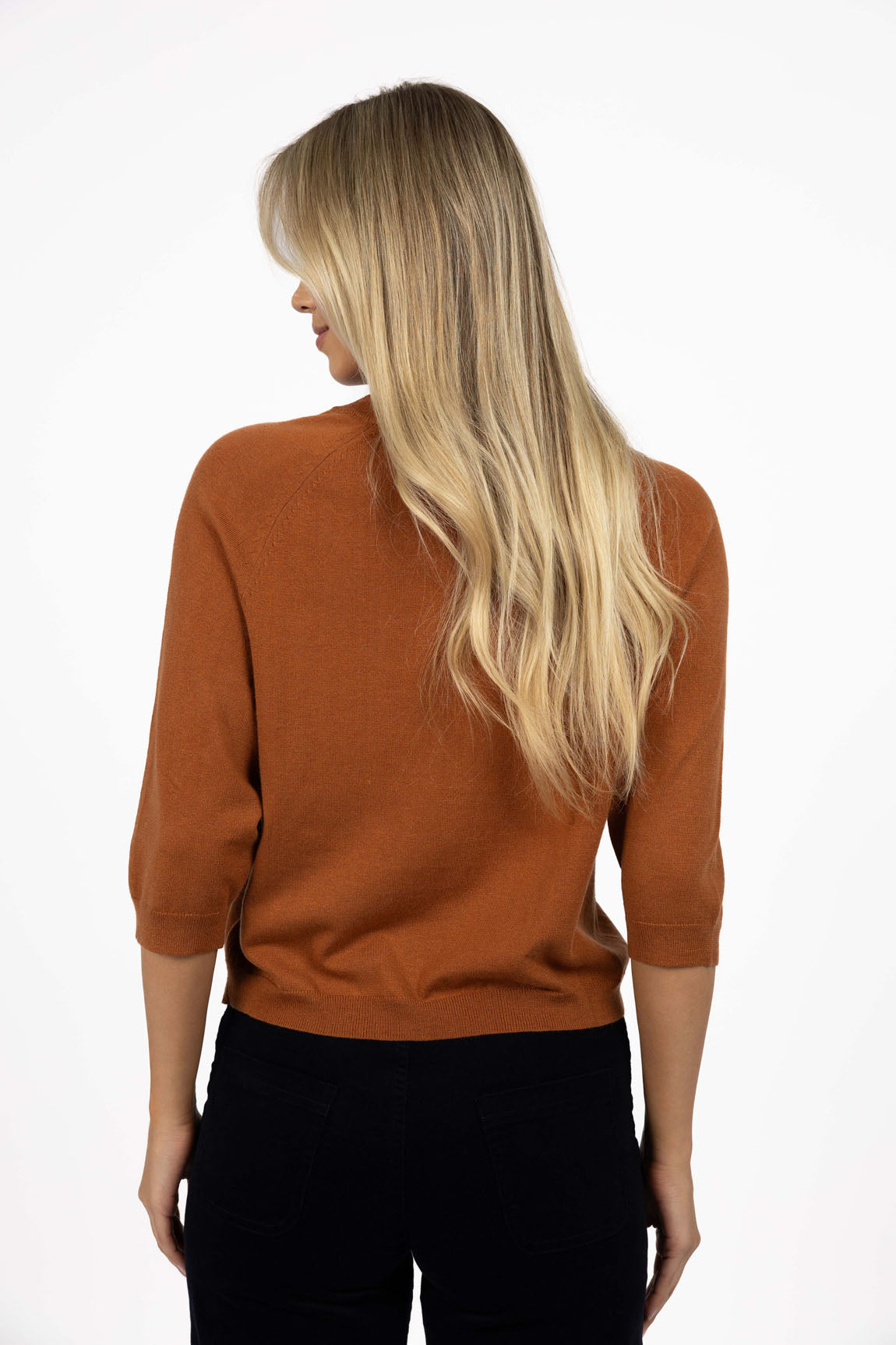 Woman wearing a Humidity top paired with black jeans on a white background