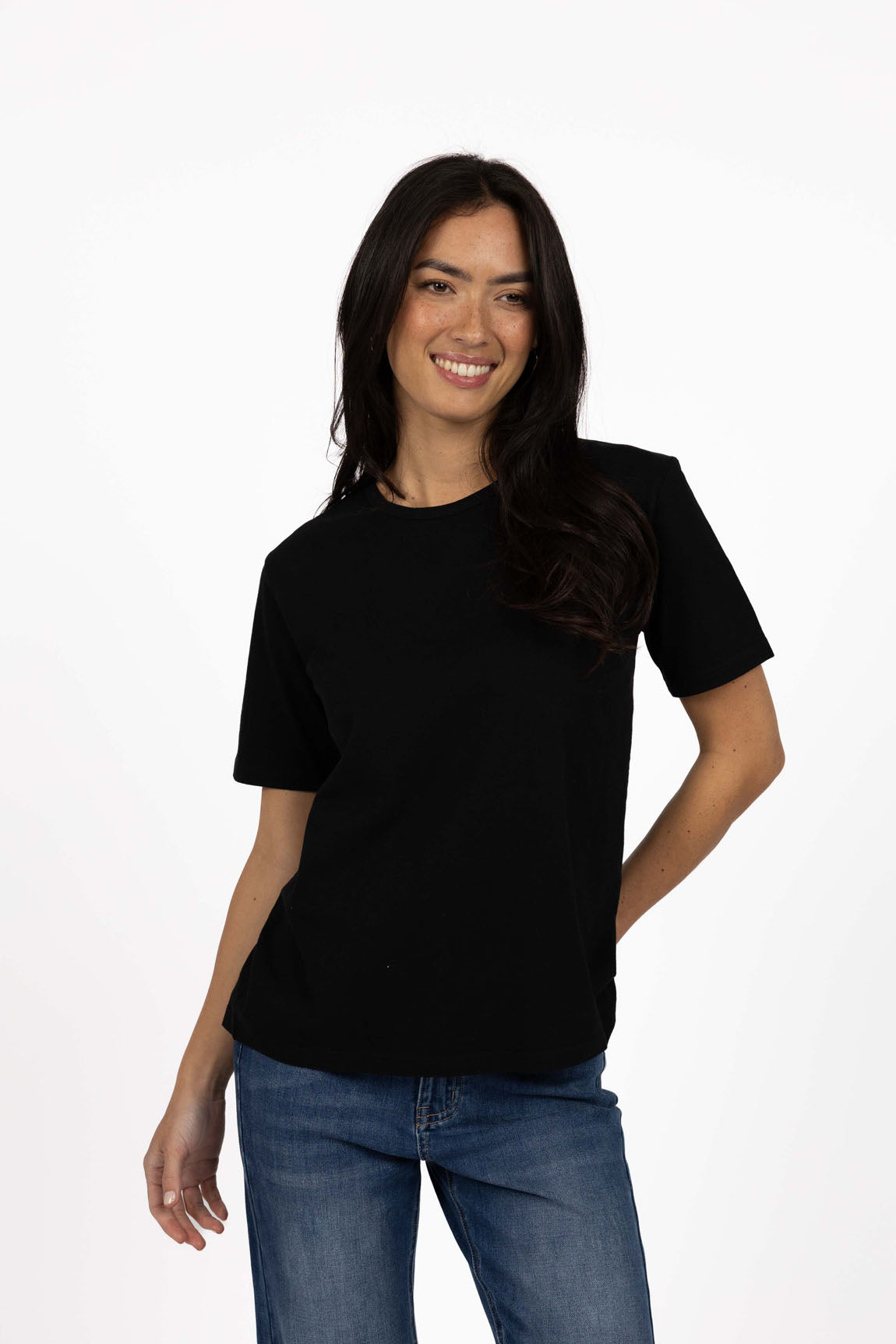 Woman wearing a Humidity black t-shirt and blue jeans on a white background