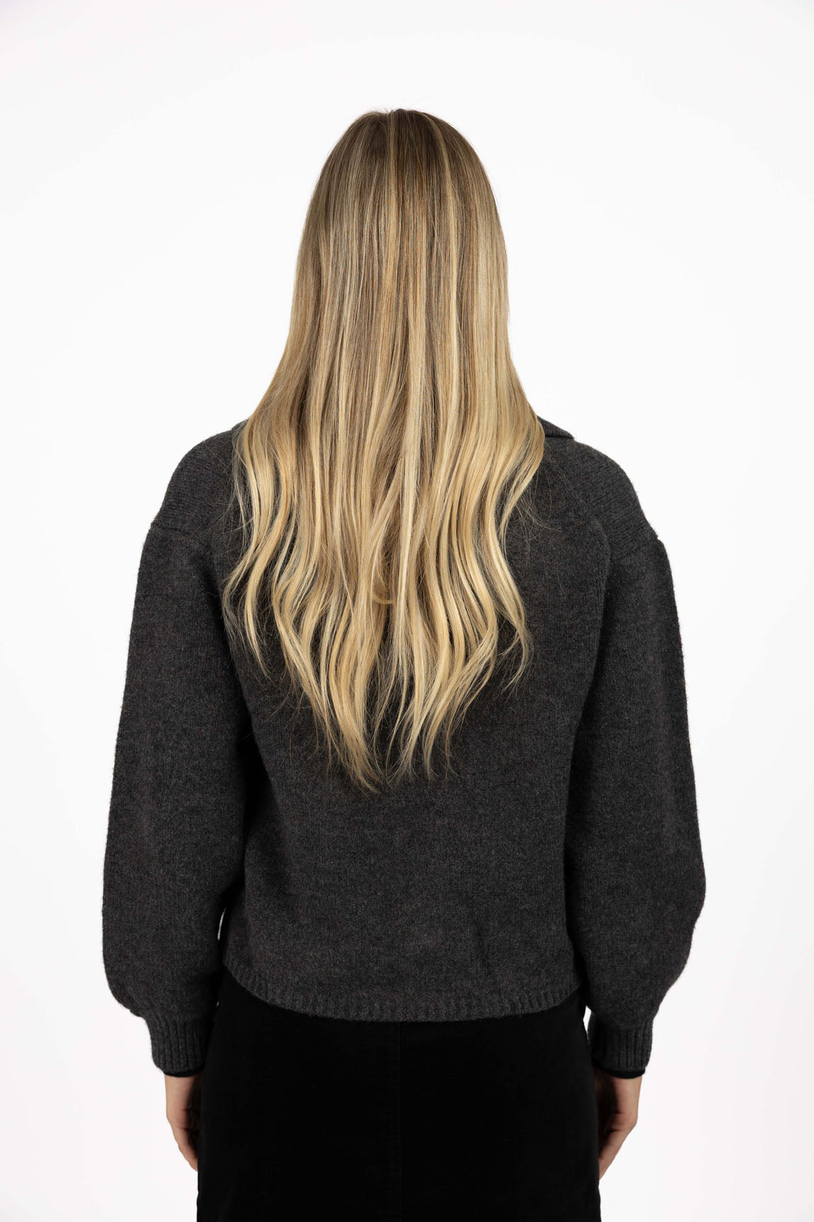 Image of Woman wearing a Humidity dark gray sweater from behind on a white background
