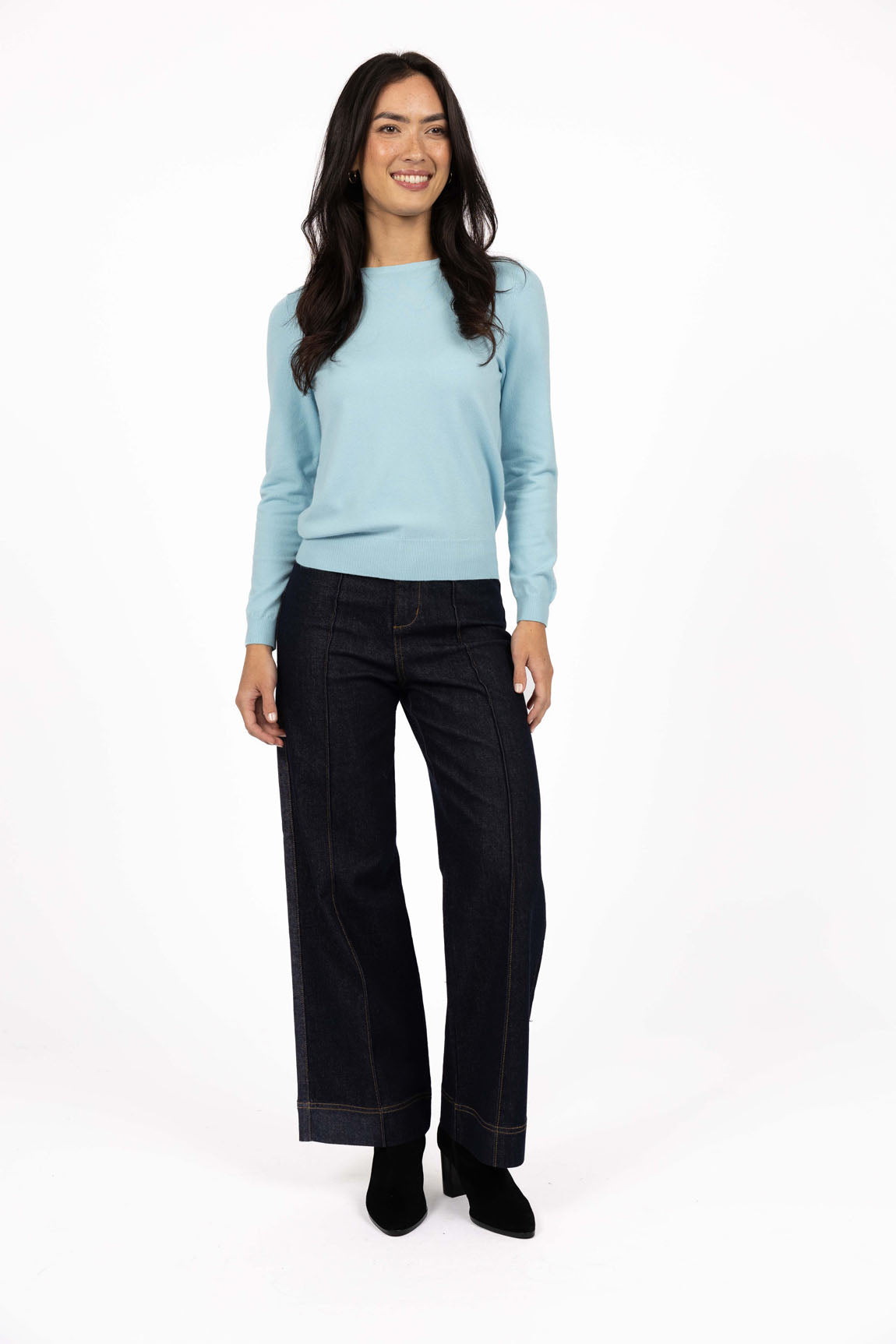 Woman wearing a Humidity light blue sweater and black pants on a white background