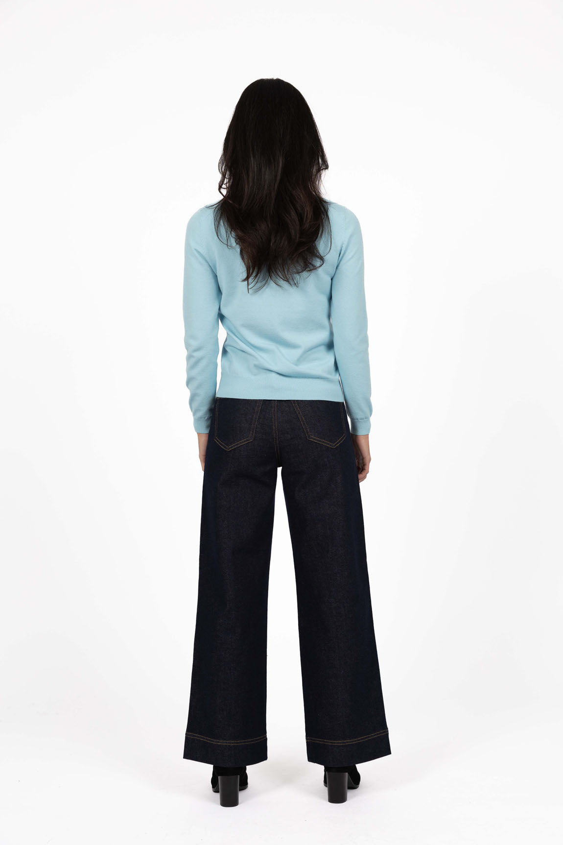 Image of Woman wearing a Humidity light blue sweater and black pants on a white background