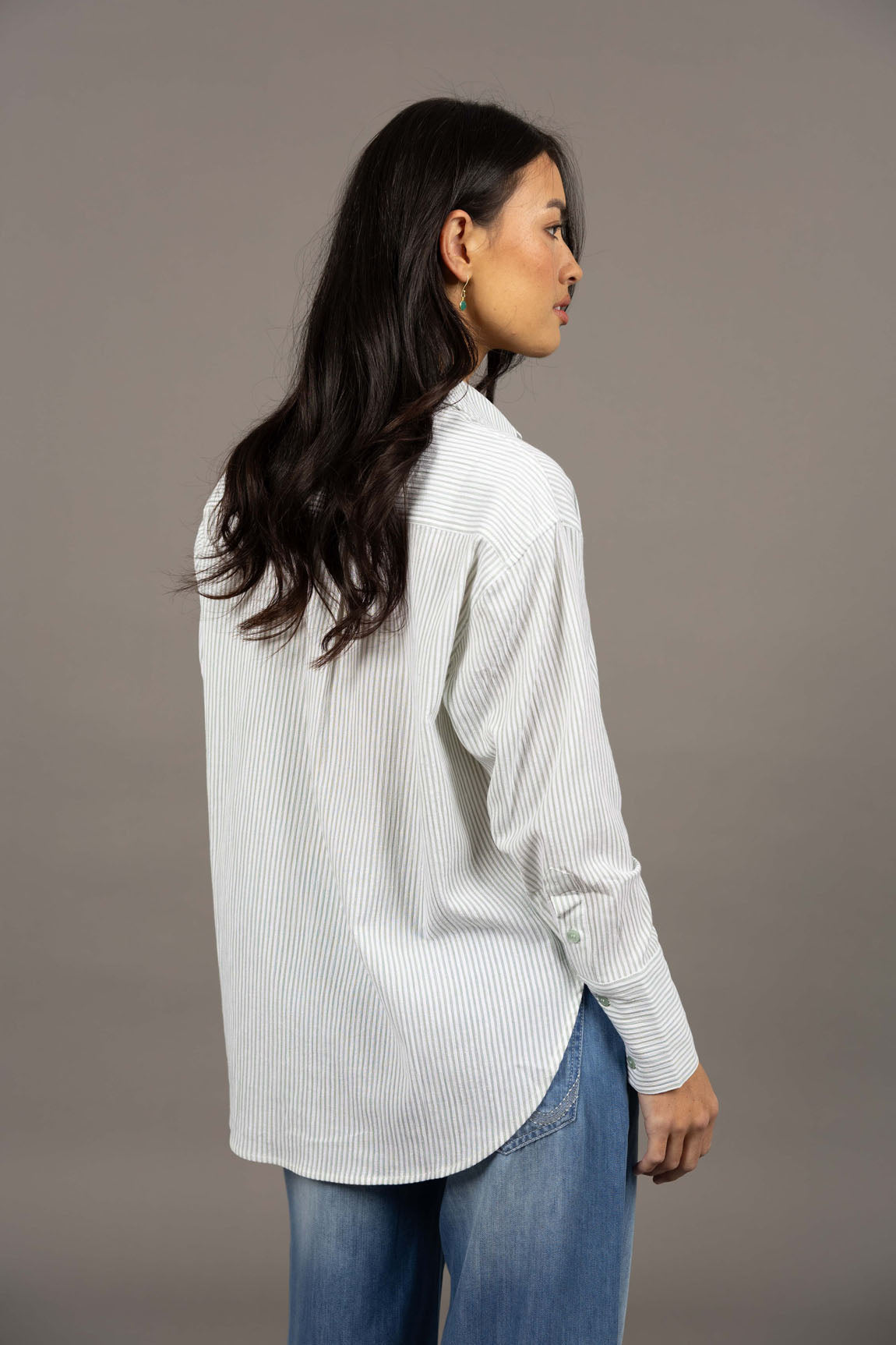 Woman wearing a Humidity green shirt and blue jeans against a gray background