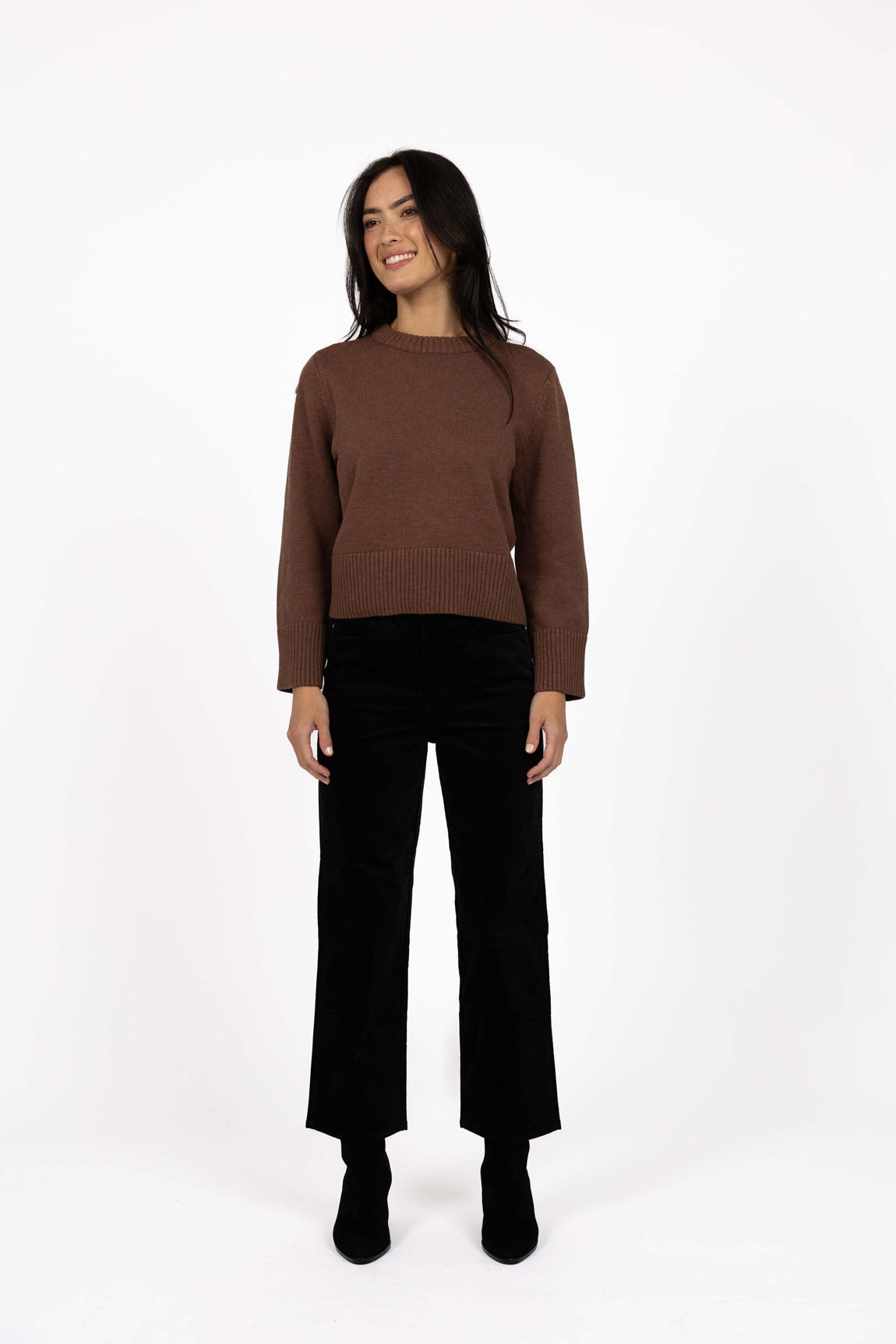Image of Woman wearing a Humidity Mocha sweater and black pants on a white background