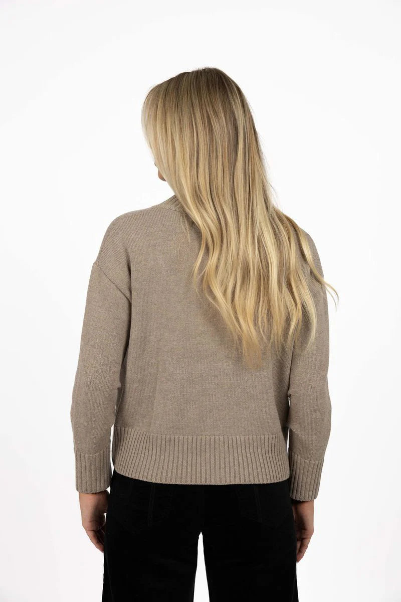 Woman wearing a Humidity beige sweater from behind on a white background