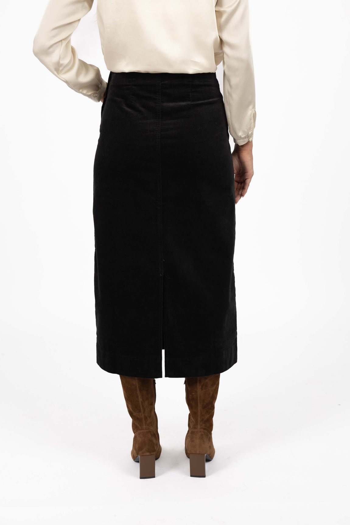 Woman wearing a Humidity black skirt and brown boots on a white background