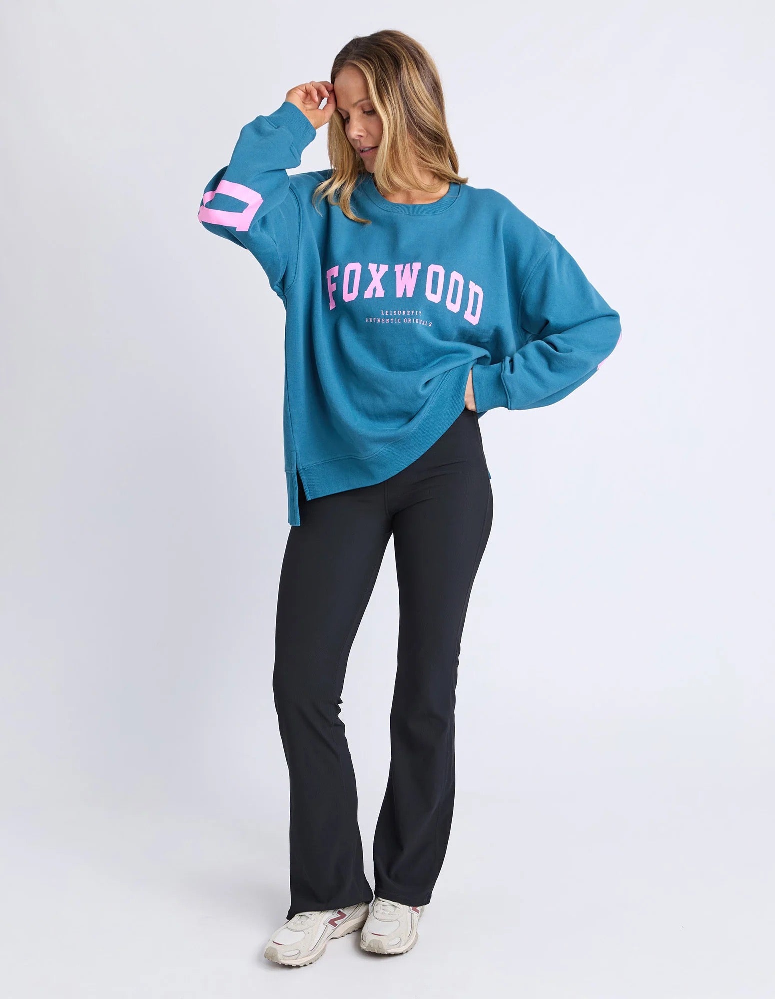 Image of Woman wearing a blue jumper with 'FOXWOOD' printed on it in pink against a white background