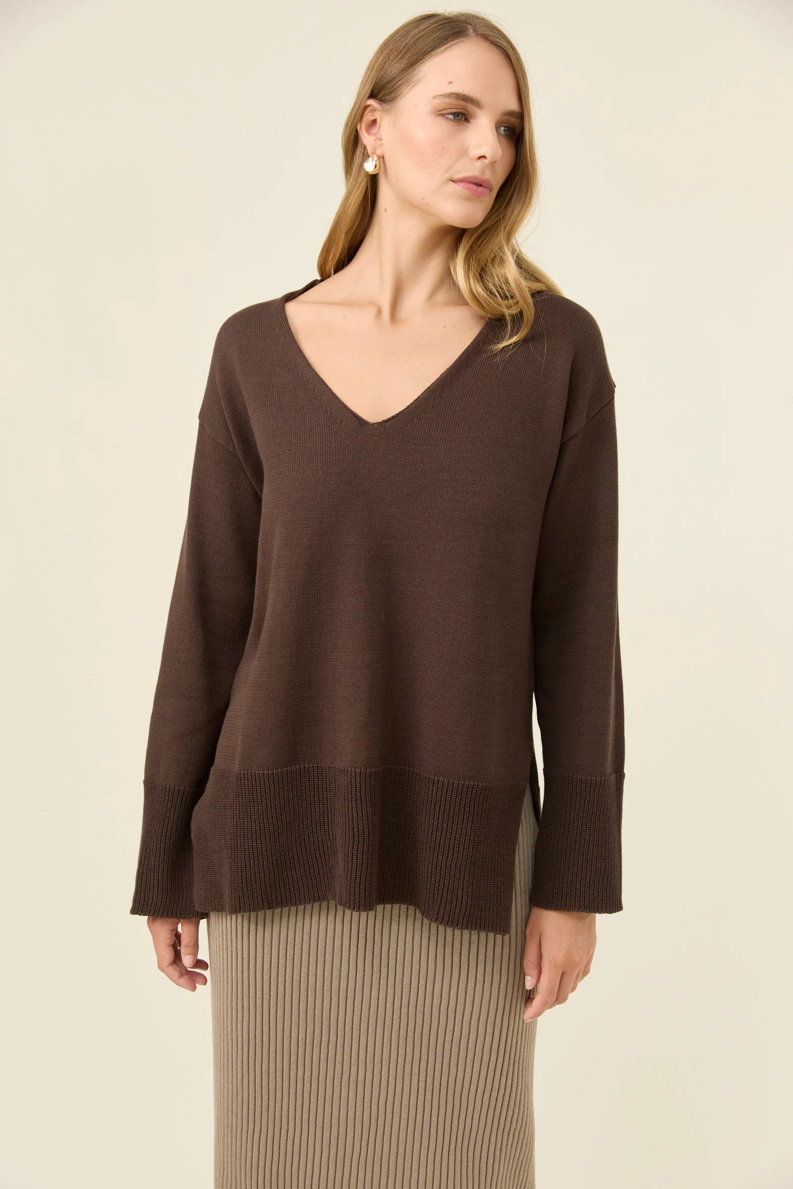 Image of Woman wearing a Isle of Mine brown sweater against a beige background
