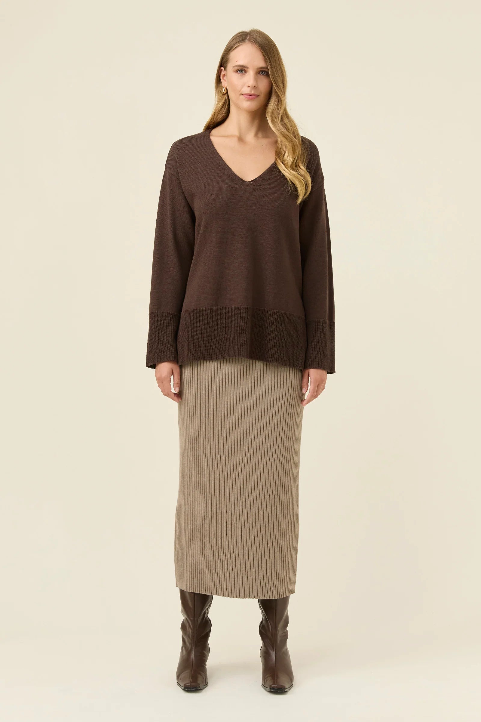 Woman wearing a Isle of Mine brown sweater and beige skirt on a beige background