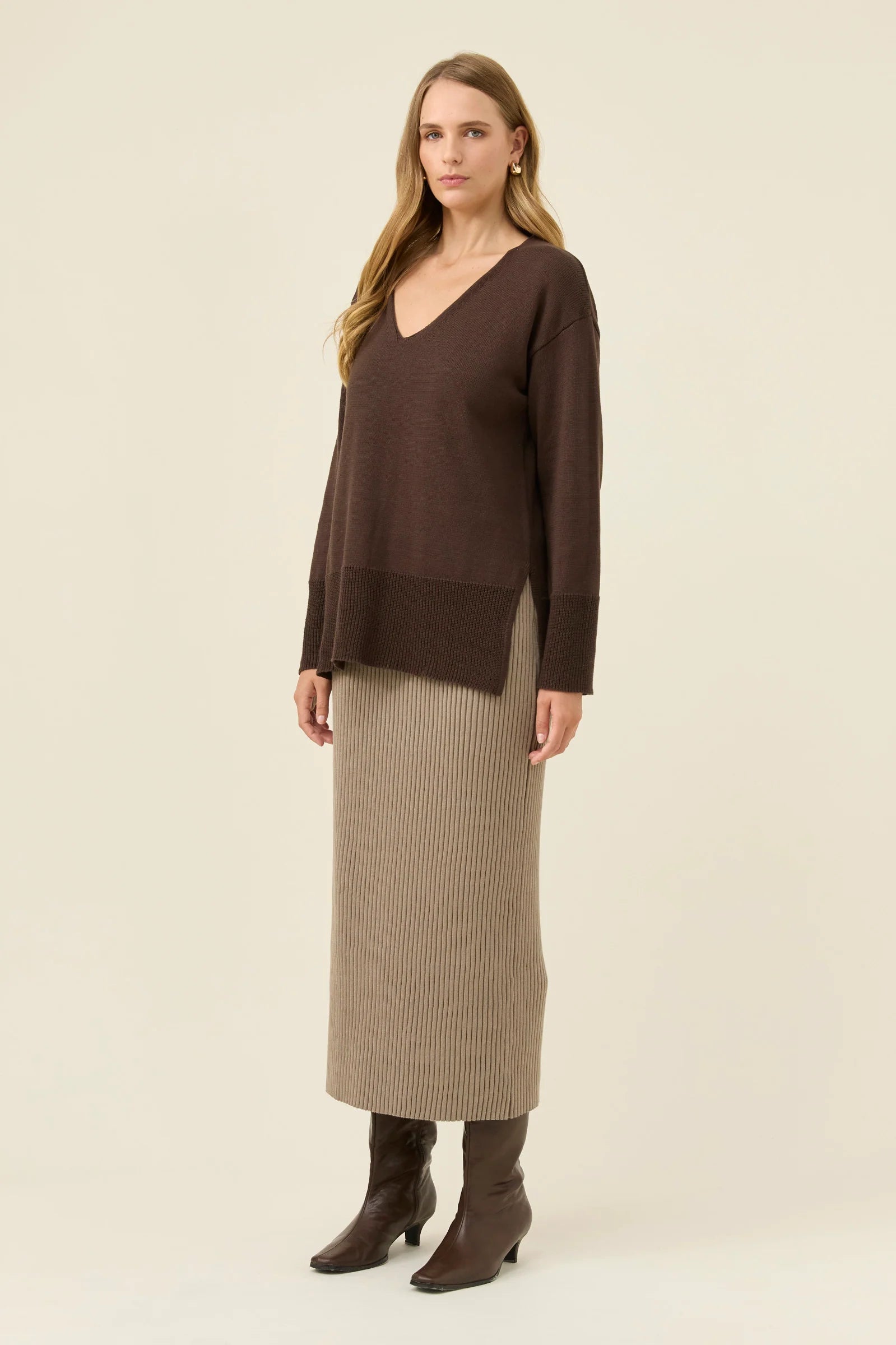 Woman wearing a Isle of Mine brown sweater and beige skirt on a white background
