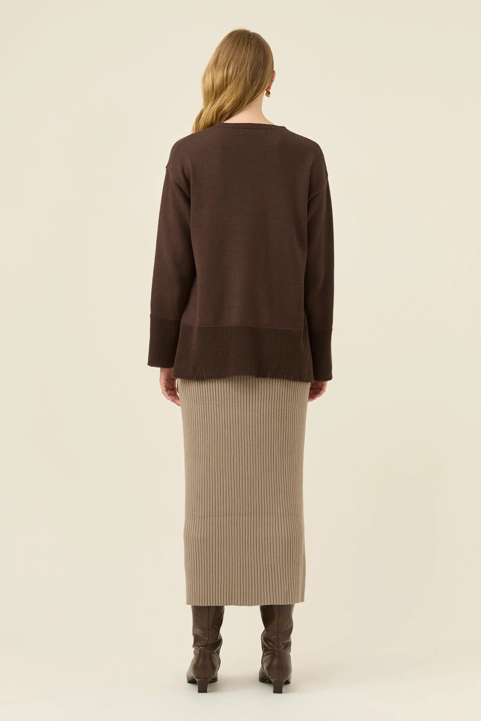 Image of Woman wearing a Isle of Mine brown sweater and beige skirt on a plain background