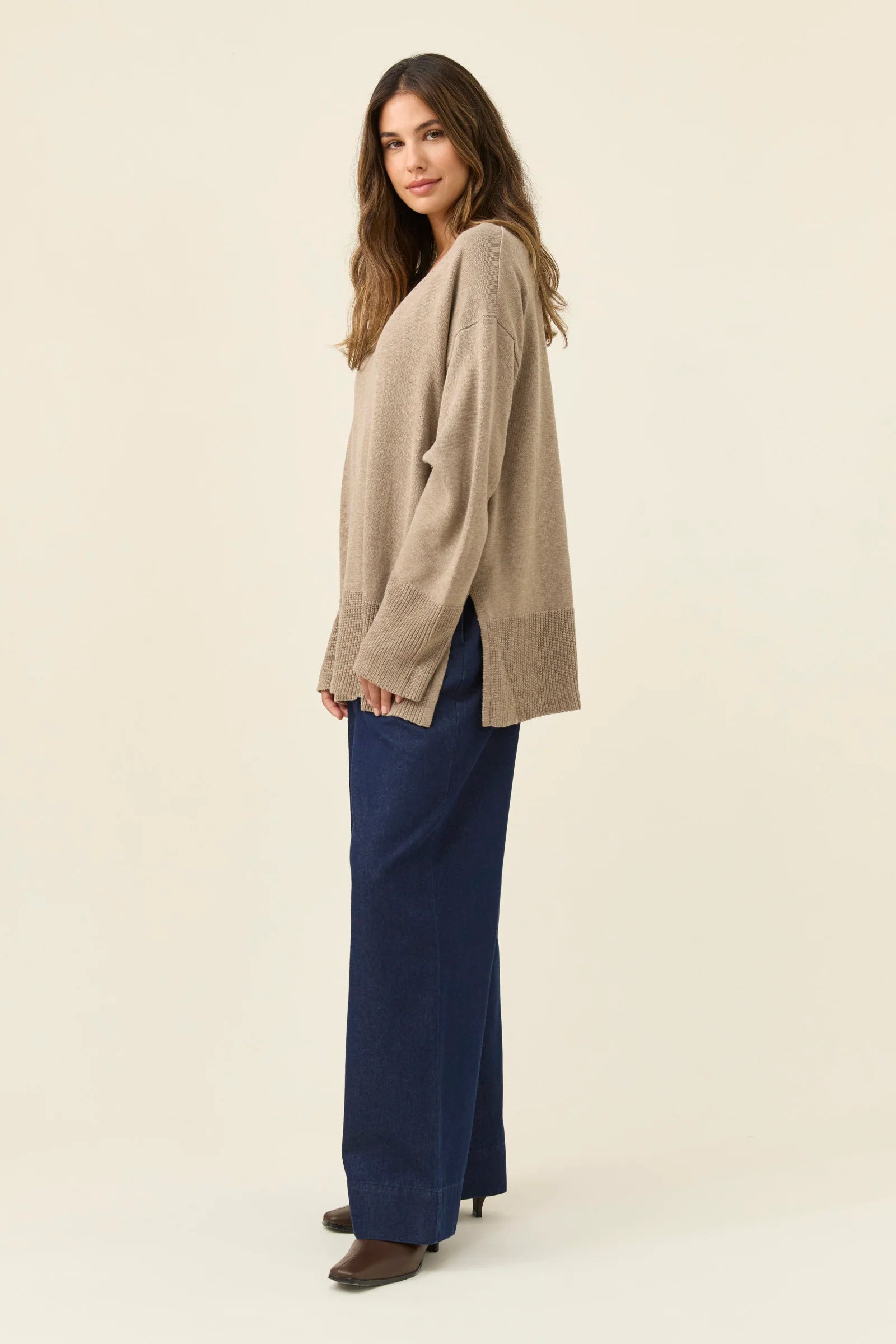 Image of Woman wearing a Isle of Mine beige sweater and navy pants on a white background