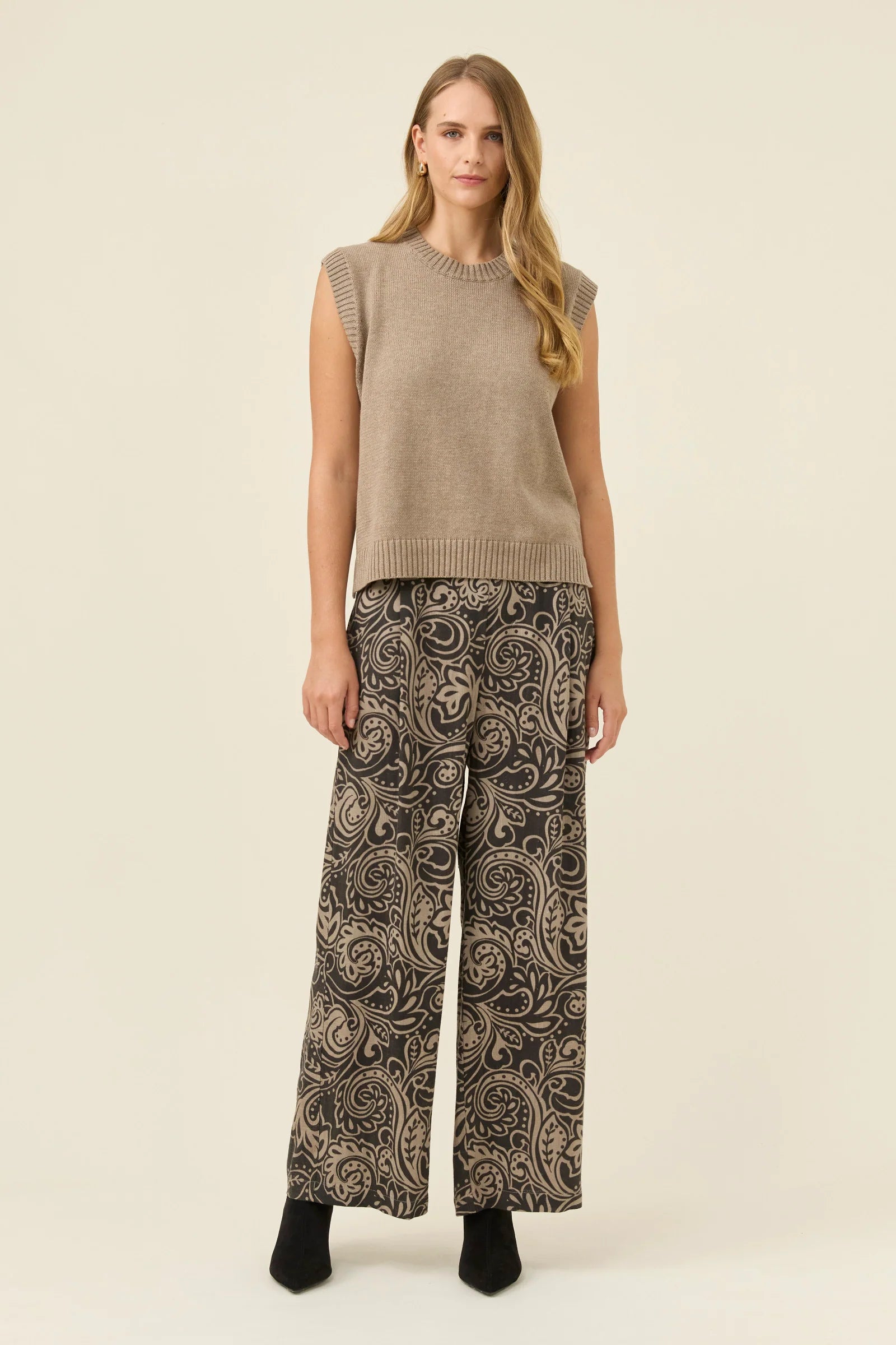 Image of Woman wearing a Isle of Mine beige sleeveless top and patterned pants on a beige background