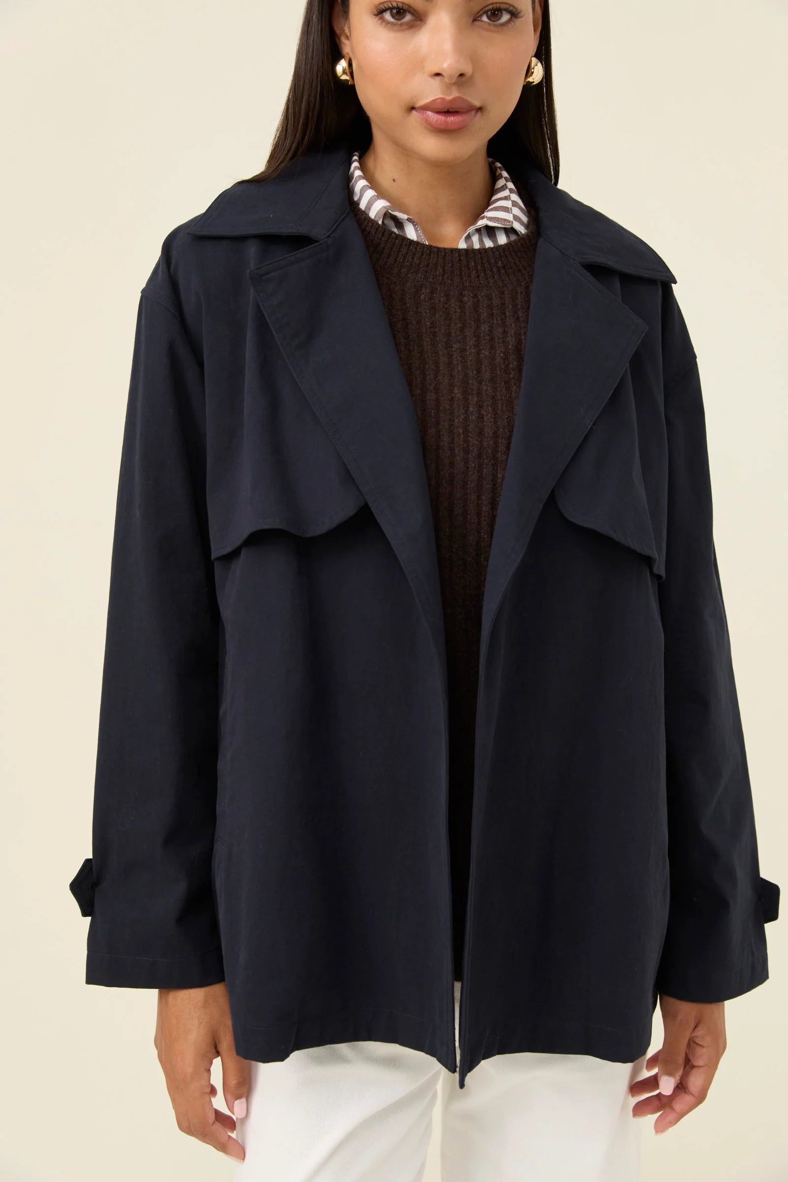 Woman wearing a Isle of Mine navy blue coat on a light pink background