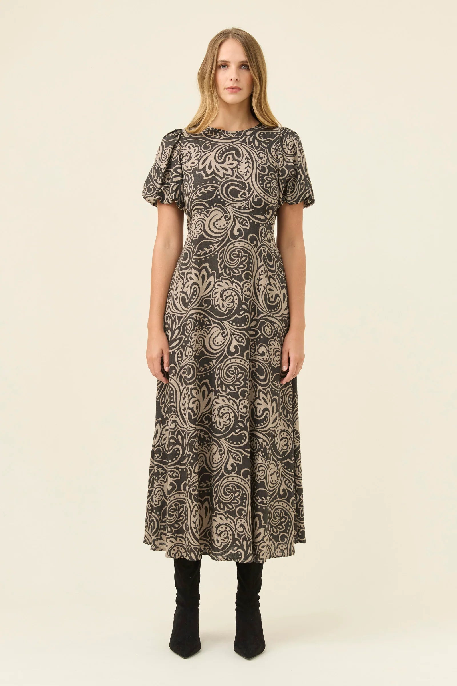 Woman wearing a Isle of Mine patterned dress on a beige background