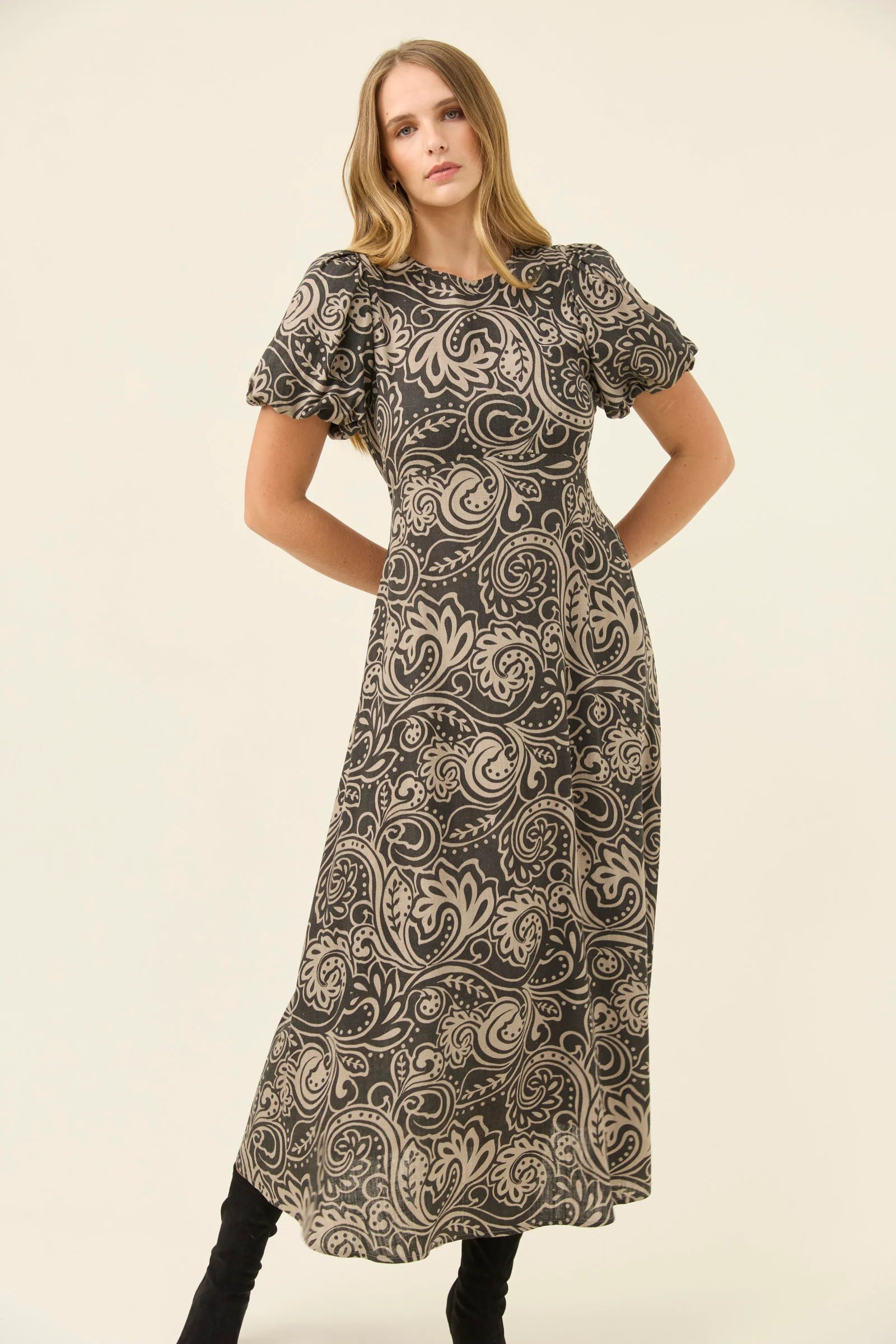 Woman wearing a Isle of Mine patterned dress on a plain background