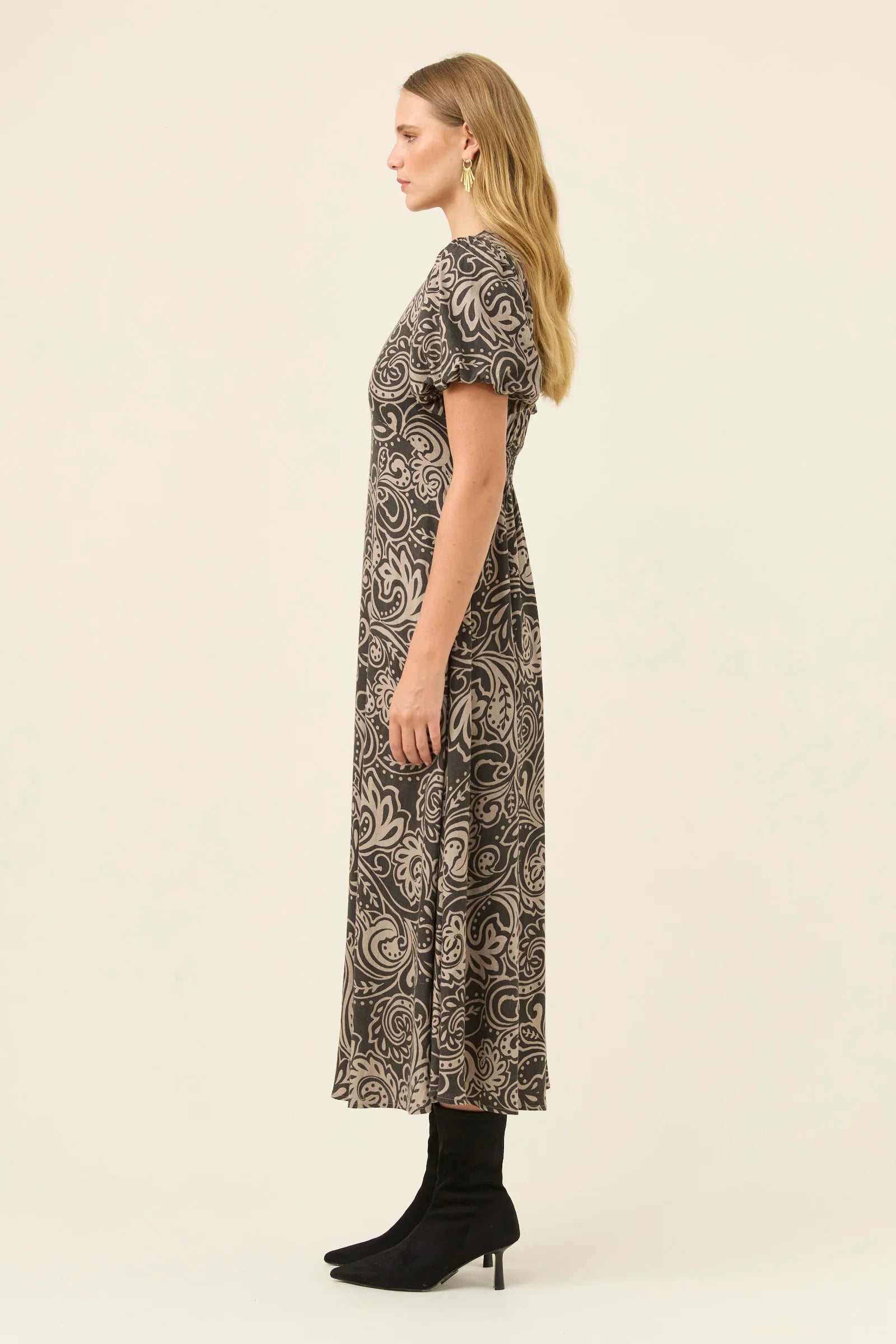 Image of Woman wearing a Isle of Mine patterned dress on a beige background