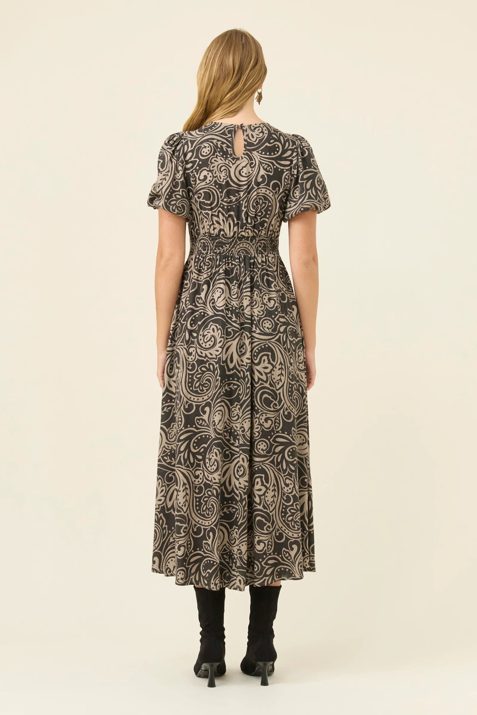 Woman wearing a Isle of Mine patterned dress on a beige background