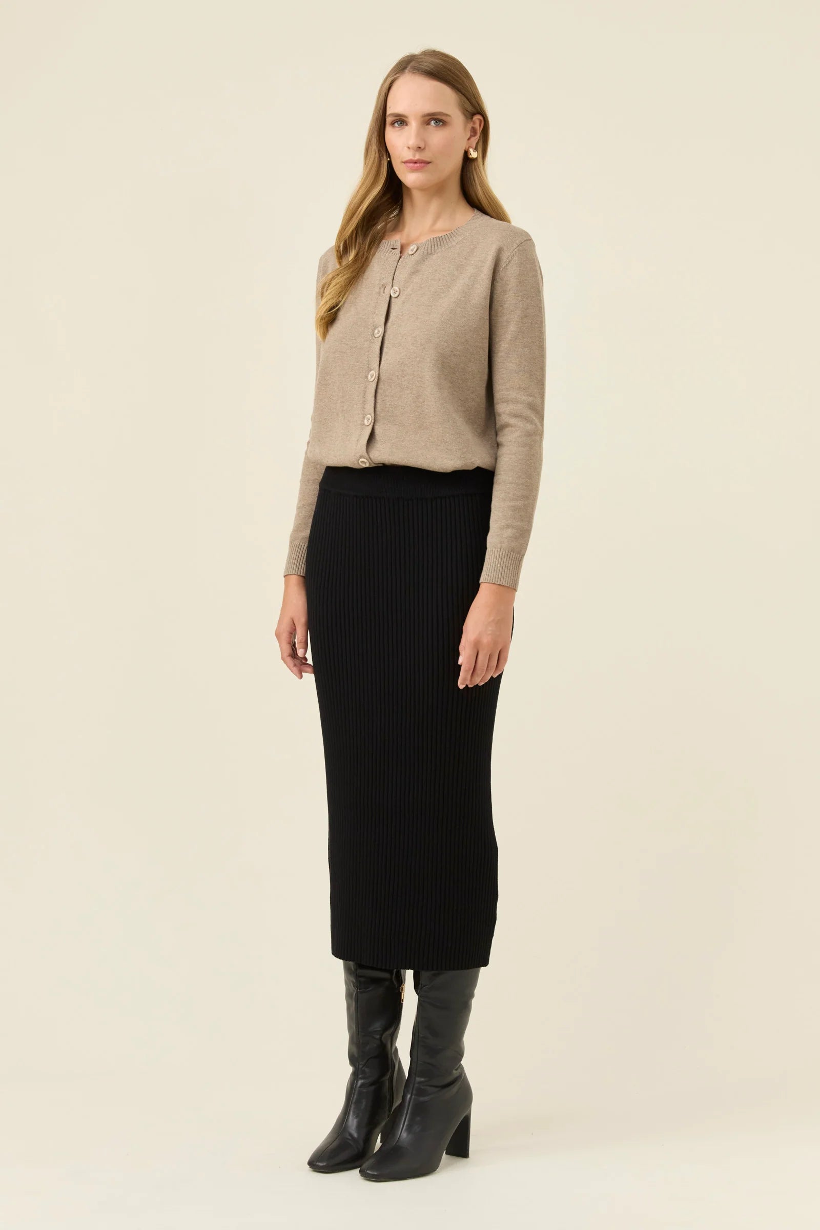 Image of Woman wearing Isle of Mine black knit skirt paired with a beige jumper on a plain background 