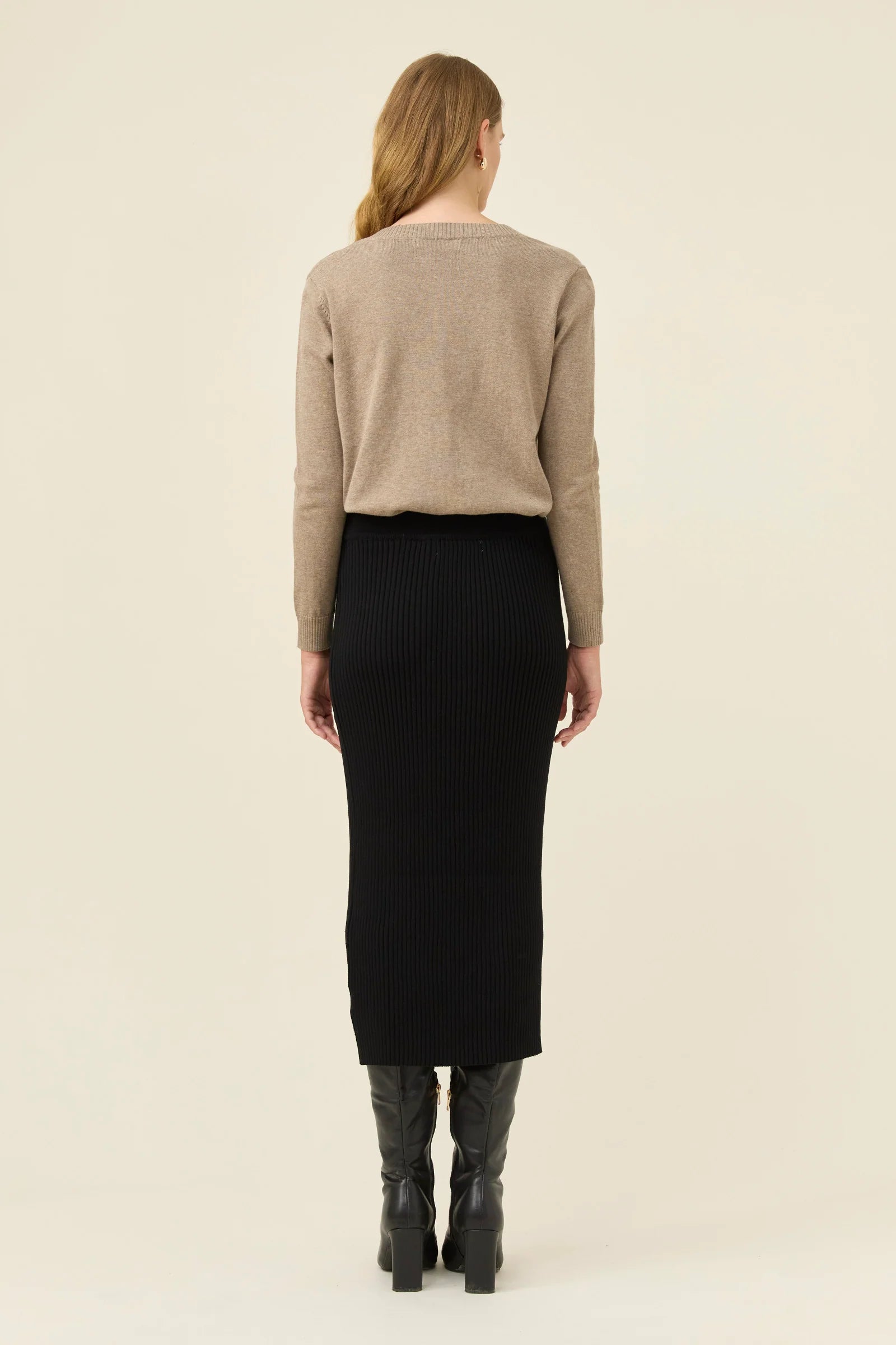 Woman wearing Isle of Mine black knit skirt paired with a beige jumper on a plain background 