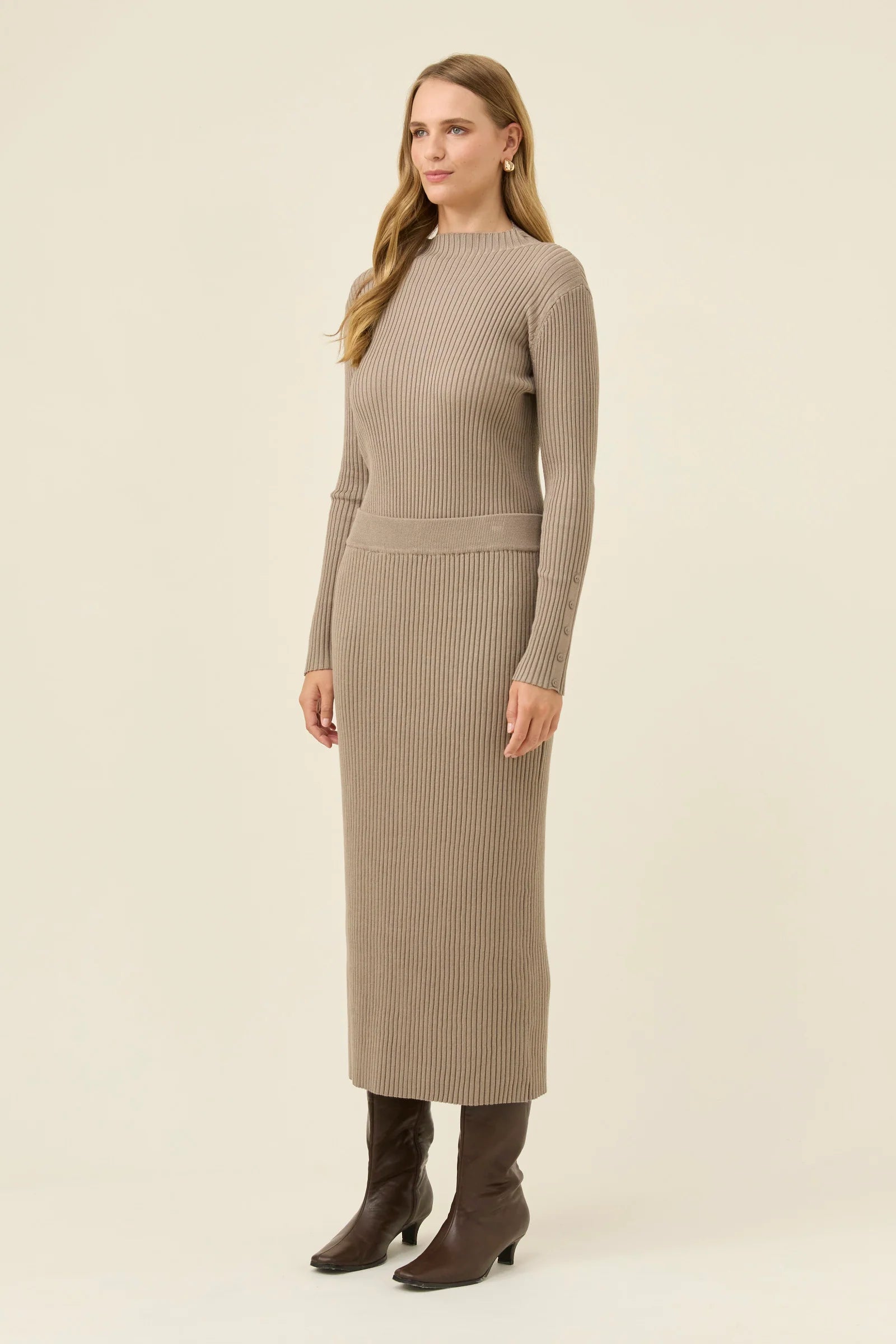 Image of Woman wearing a Isle of Mine beige ribbed skirt with brown boots on a white background